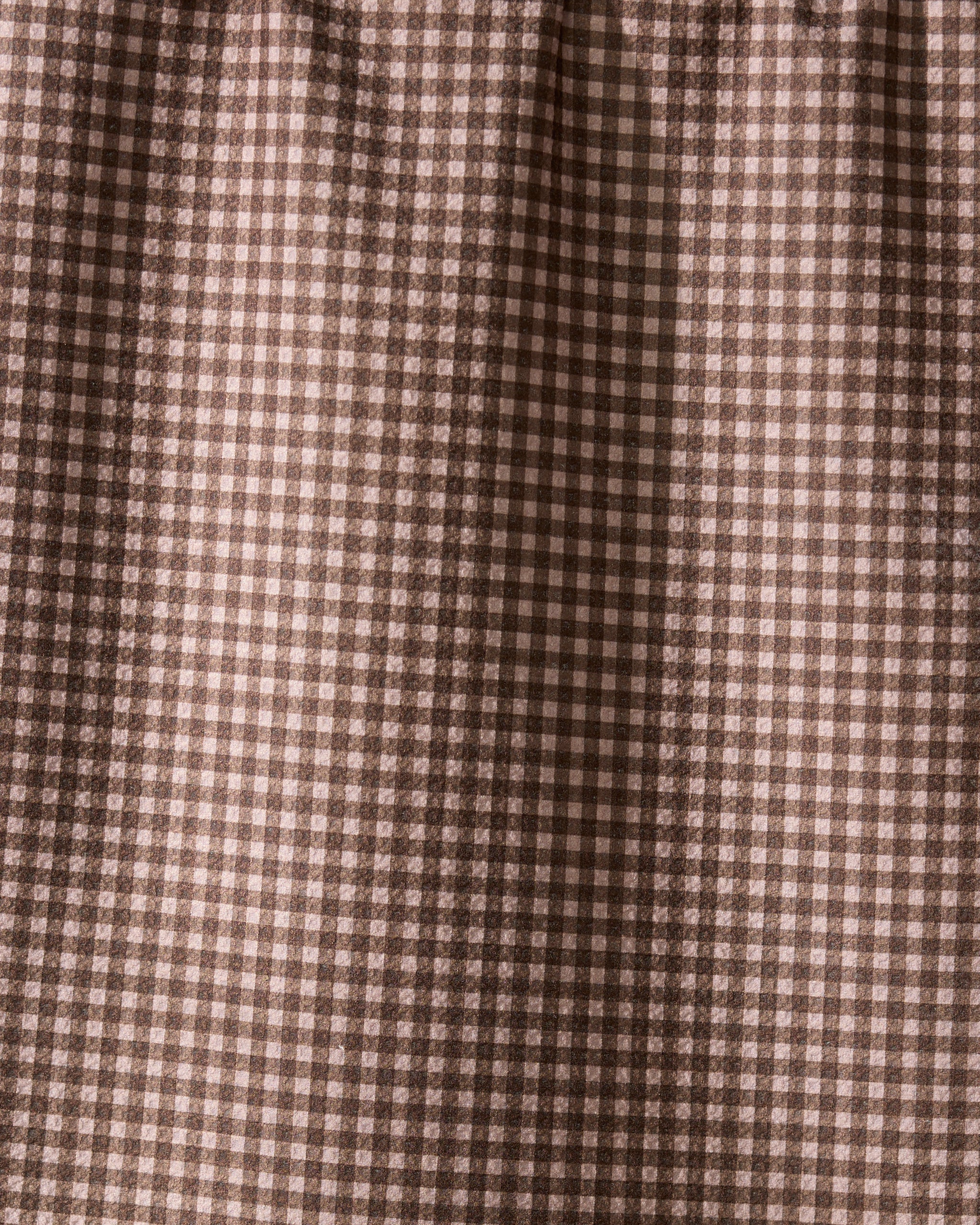 Close-up of Hearth by Geometry, a recycled kitchen towel featuring a brown and cream gingham check with small squares in a repeating grid. The fabric is softly gathered at the top, highlighting its eco-friendly design.
