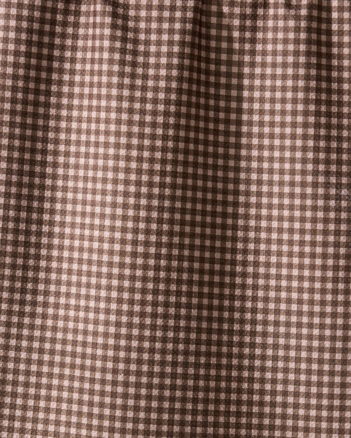 Close-up of Hearth by Geometry, a recycled kitchen towel featuring a brown and cream gingham check with small squares in a repeating grid. The fabric is softly gathered at the top, highlighting its eco-friendly design.