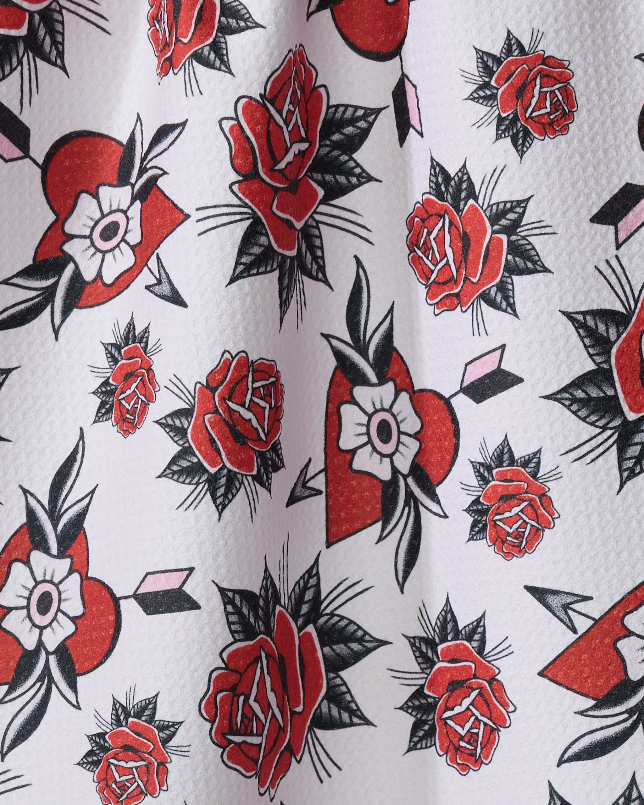 Hearts and Roses by Cole Strem features tattoo-inspired red roses, hearts with white flowers, and pink arrows on a light textured background—repeating across this recycled kitchen towel for style and sustainability.