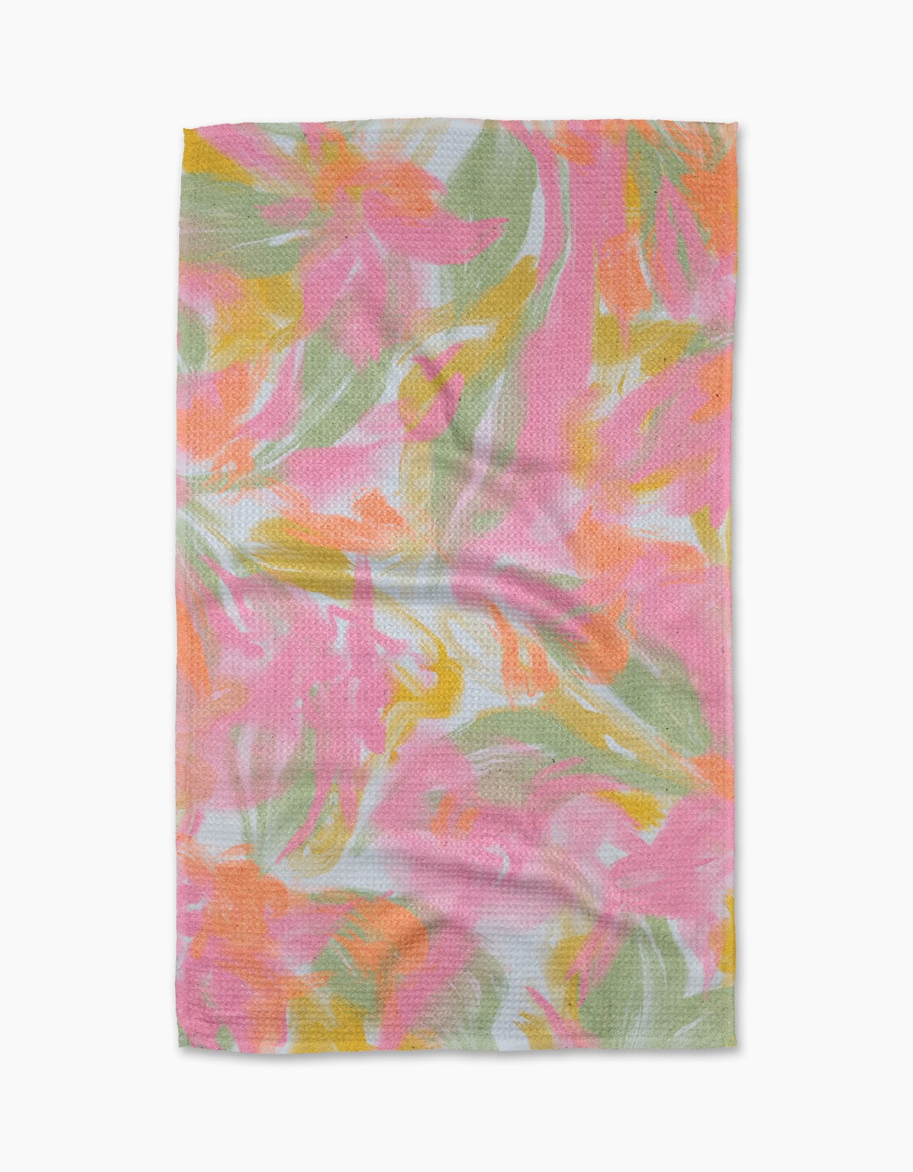 The Geometry Heat Wave tea towel features an abstract floral pattern in pink, orange, yellow, and green on a light background, crafted from textured Geoweave fabric with slight wrinkles.