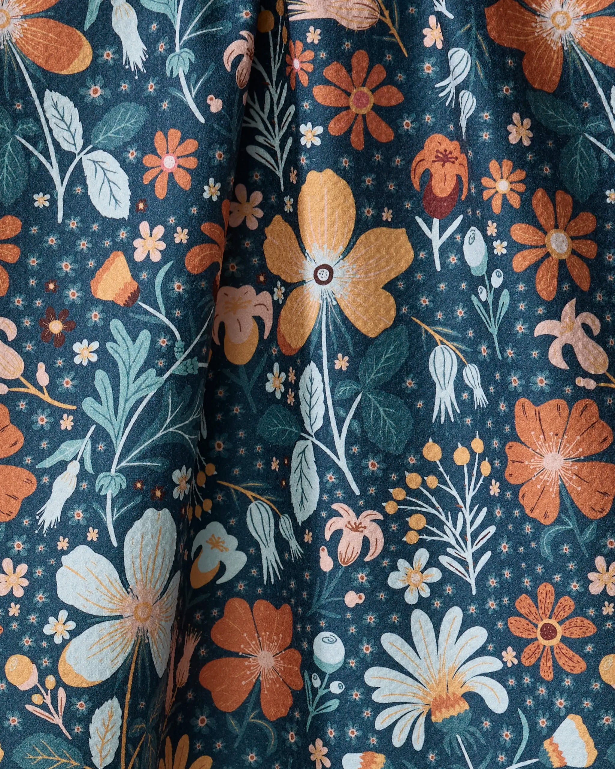 Helle Bore by Danelys Sidron features a vibrant botanical floral print with orange, yellow, and white flowers on dark blue. Made from ultra-absorbent, recycled materials, this whimsical fabric is ideal for kitchen tea towels.