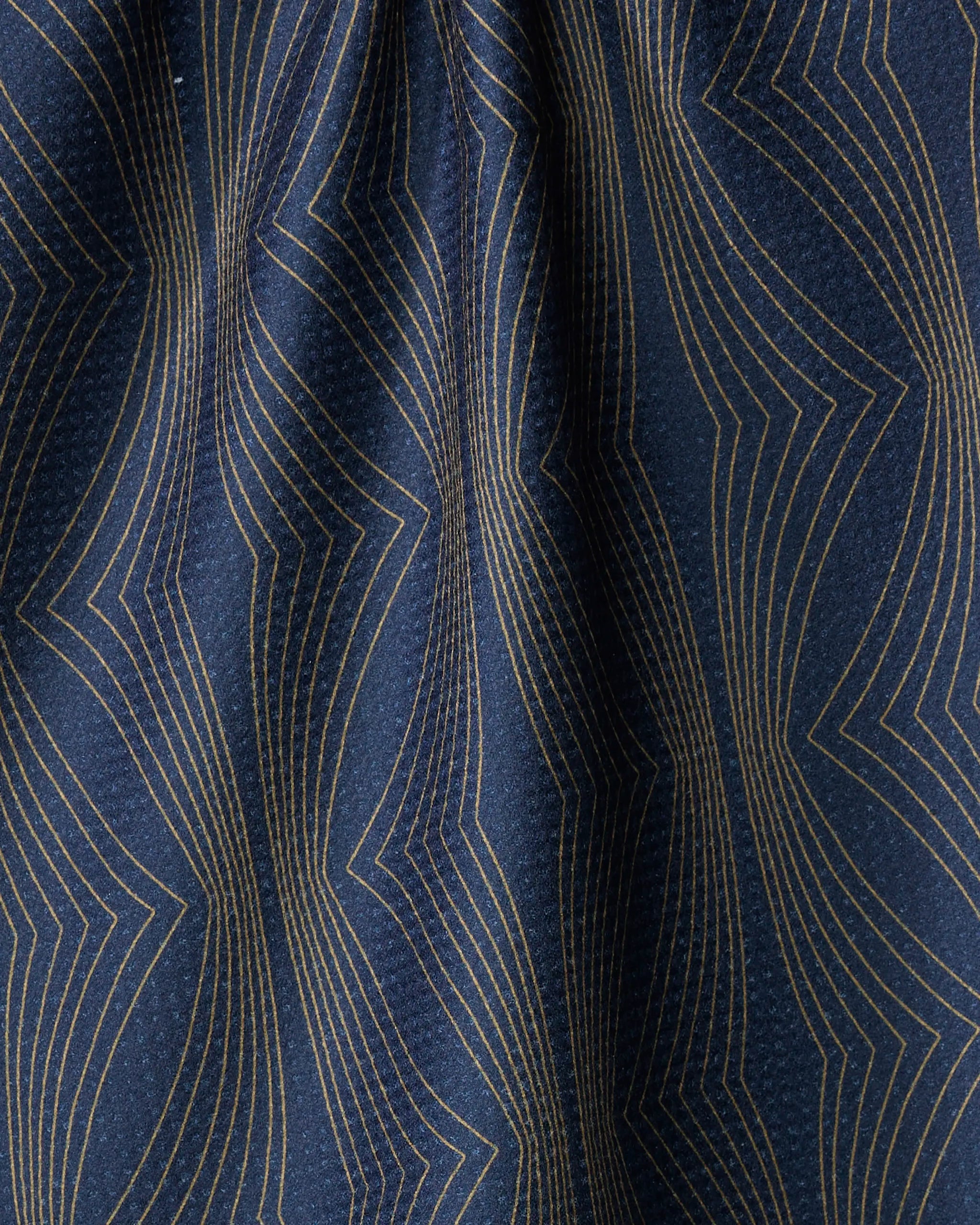 A close-up of the Hera tea towel by Amy MacCready, featuring dark blue ultra-absorbent fabric with gold geometric zigzag lines and gentle folds that create subtle shadows and depth.