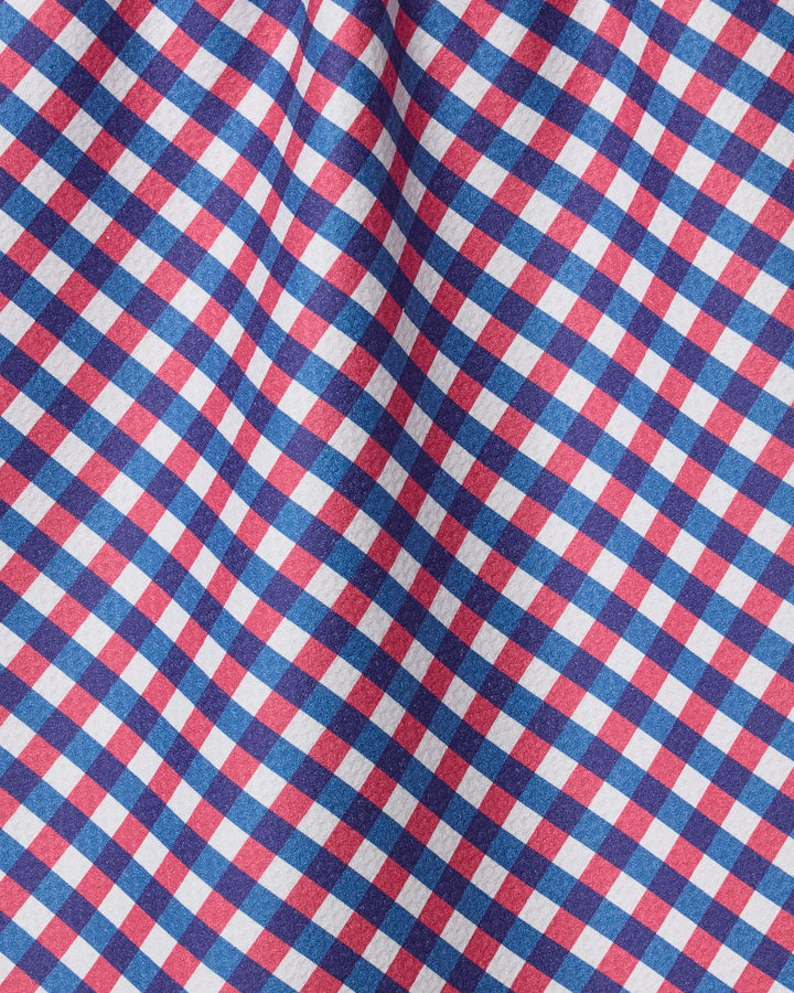 A close-up of the Geometry Heritage Check tea towel reveals a vibrant red, blue, and white plaid pattern in diagonal rows. The slightly wrinkled, ultra-absorbent fabric highlights the towel’s charm and quality.