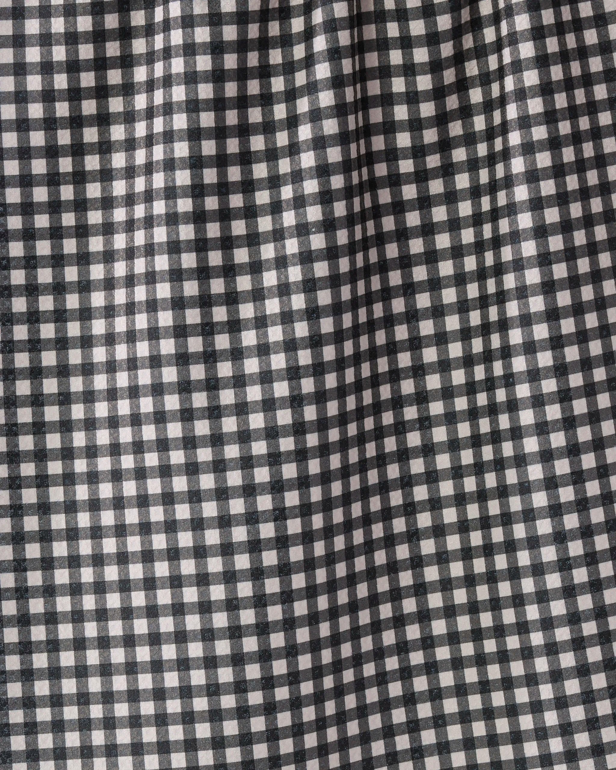 A close-up of Geometry's Heritage kitchen towel fabric features a black and white checkered grid pattern, highlighting subtle folds and shadows for a textured, eco-friendly look.