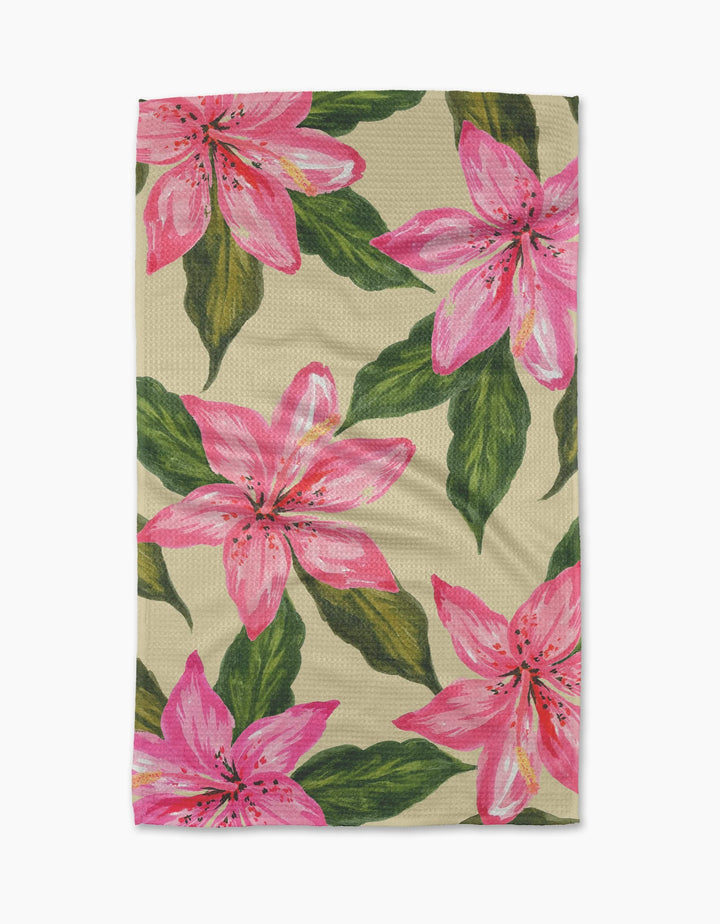 The Geometry Hibiscus Haze Kitchen Tea Towel features a beige background with vibrant pink lilies and green leaves, crafted from durable Geoweave fabric for enhanced absorbency.