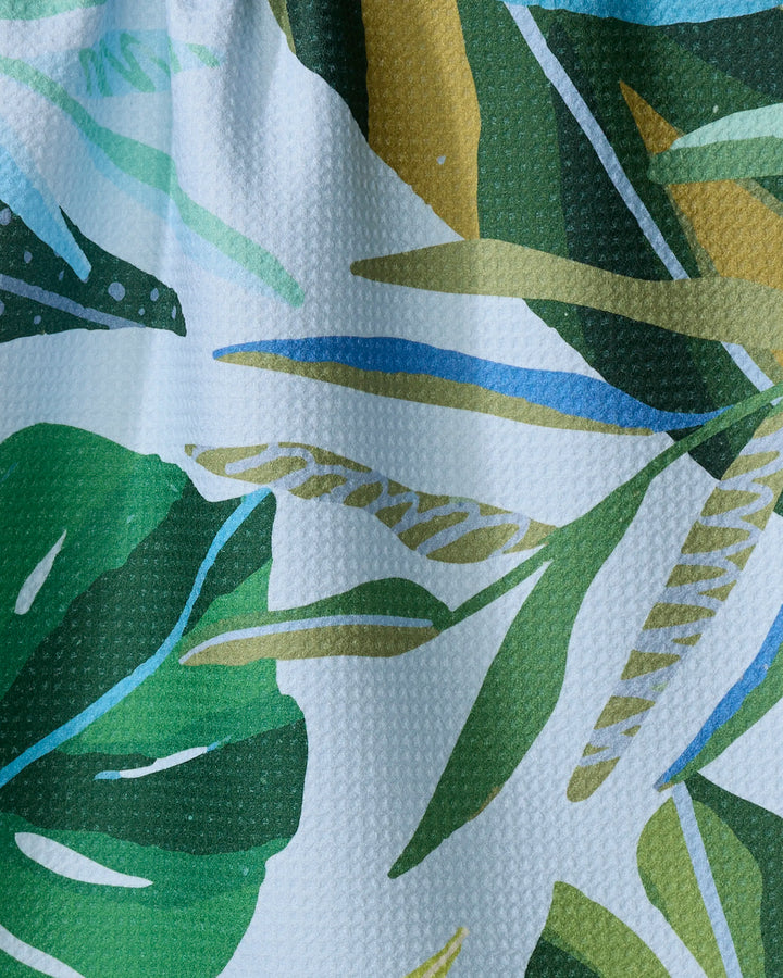 Close-up of the Hidden Island ultra-absorbent tea towel by Janna Sue Design, featuring a textured fabric with green, blue, yellow, and white tropical leaves in various shapes—perfect for adding a vibrant accent to your kitchen.
