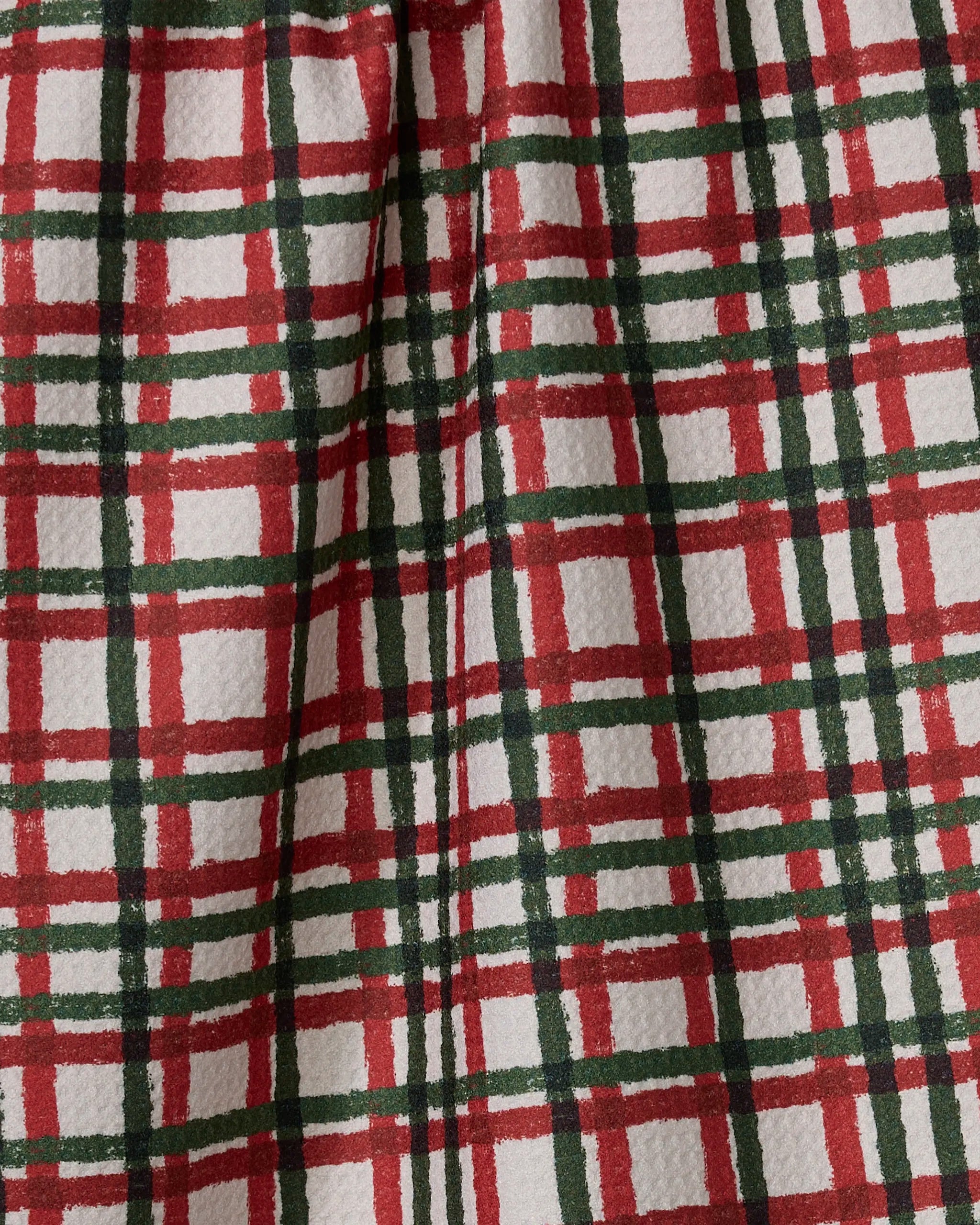 A close-up of Holiday Charm by Geometry, showcasing a red, green, and white plaid fabric—classic intersecting lines perfect for a timeless tea towel.