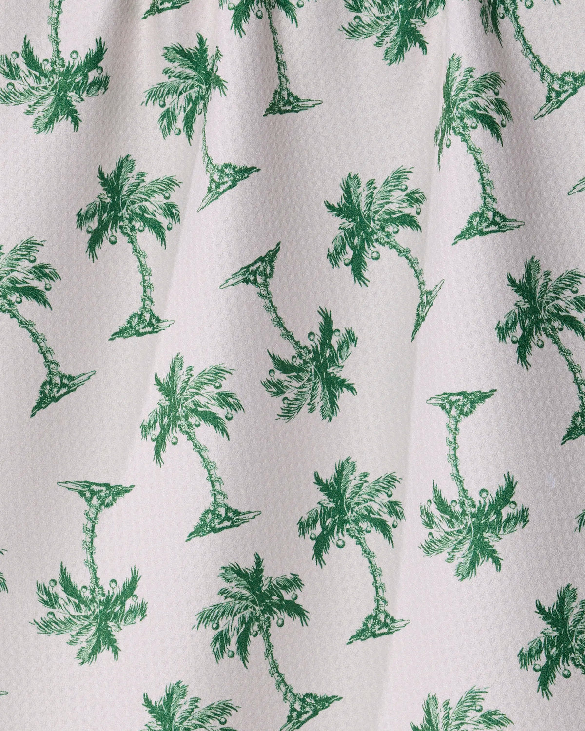 Holiday Hideaway by Geometry features a white, textured fabric adorned with an evenly spaced pattern of green palm trees—some upright and some upside down. This quick-drying towel blends playful design with everyday practicality, making it ideal for daily use.