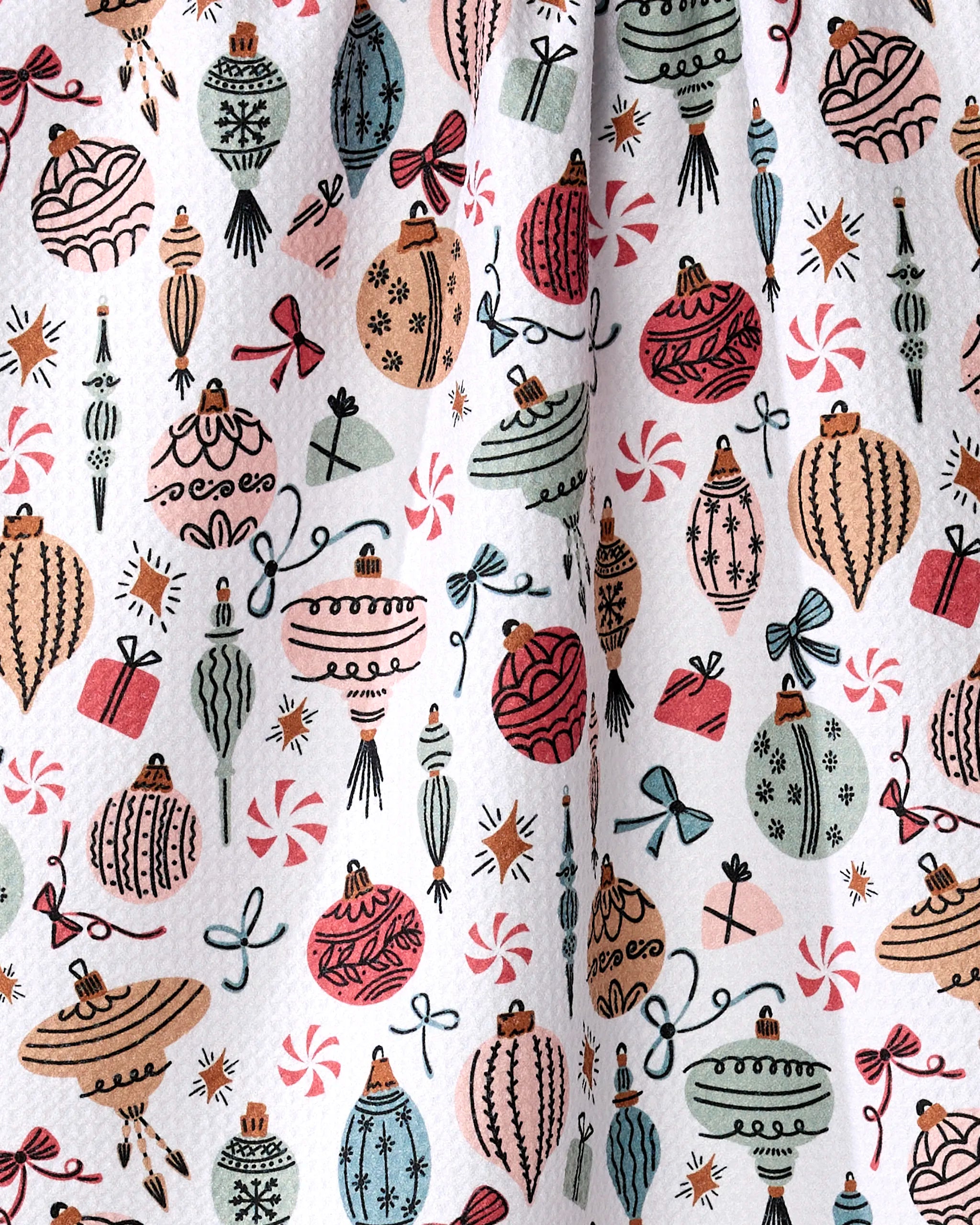 The "Holiday Ornaments" kitchen towel by Charlie Rowan Designs features a textured fabric with festive ornaments, bows, presents, and candy in red, green, pink, and white—perfect for bringing holiday cheer to your kitchen.