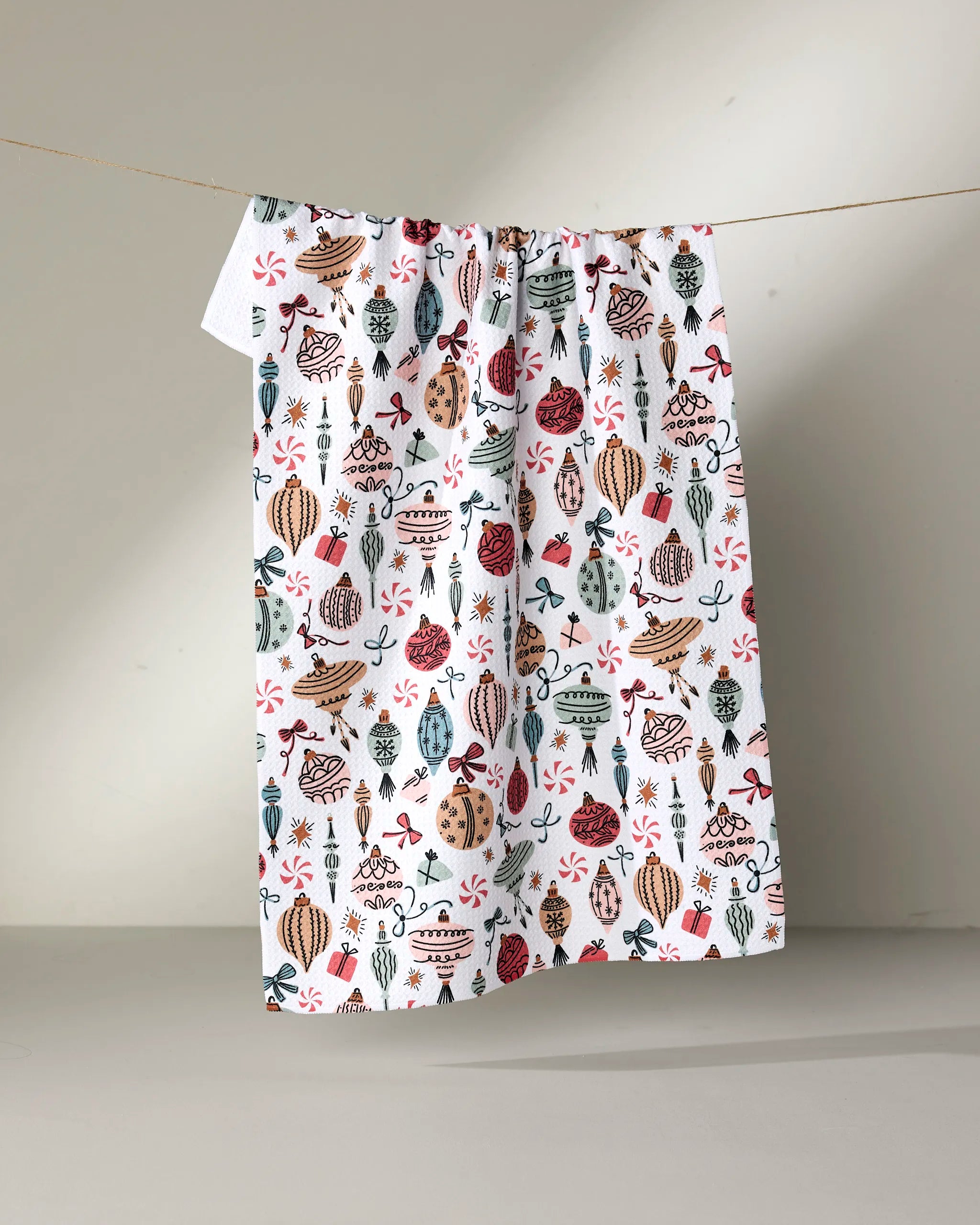 The "Holiday Ornaments" kitchen towel by Charlie Rowan Designs is made from recycled materials and displays whimsical pots, vases, and plants in red, green, brown, and blue on a white background.
