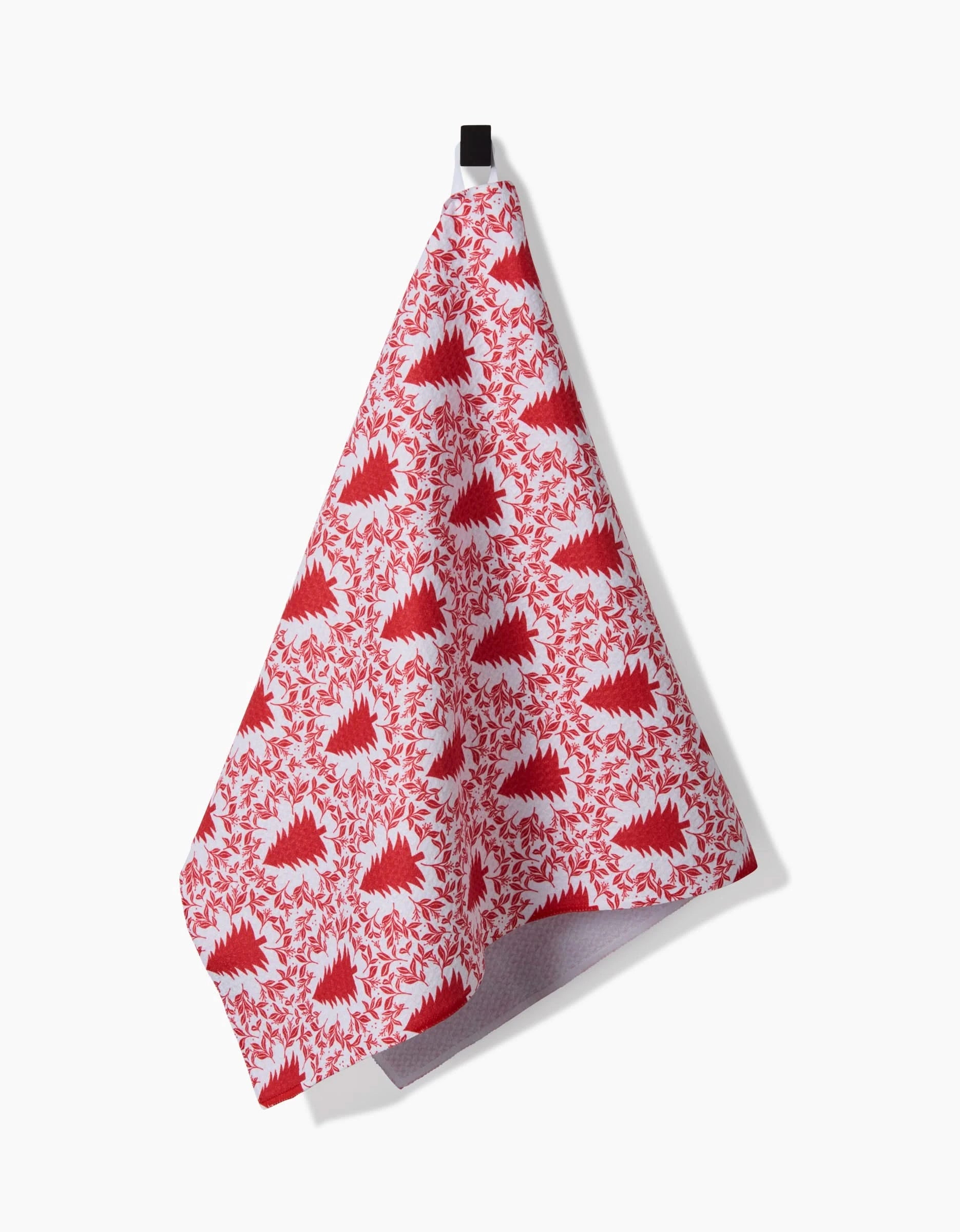 The Holiday Tree white tea towel by Charlie Rowan Designs features a quick-drying fabric and a red stylized tree and leaf pattern, hanging from a black loop against a plain white background.