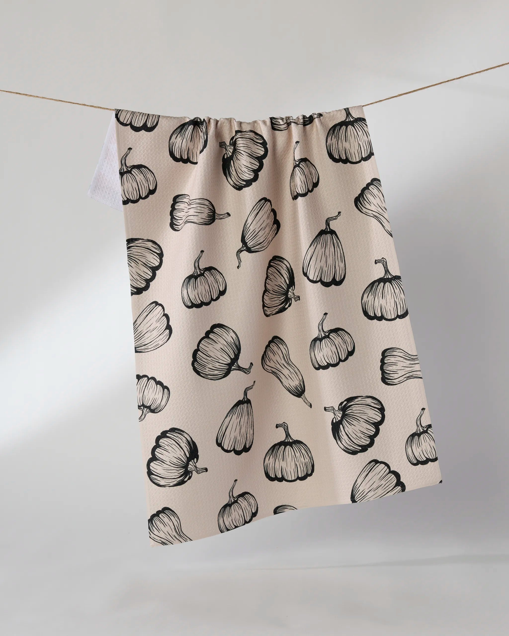 The Geometry Hollow Season kitchen towel, made from recycled materials, features a black pumpkin pattern and hangs against a light background.