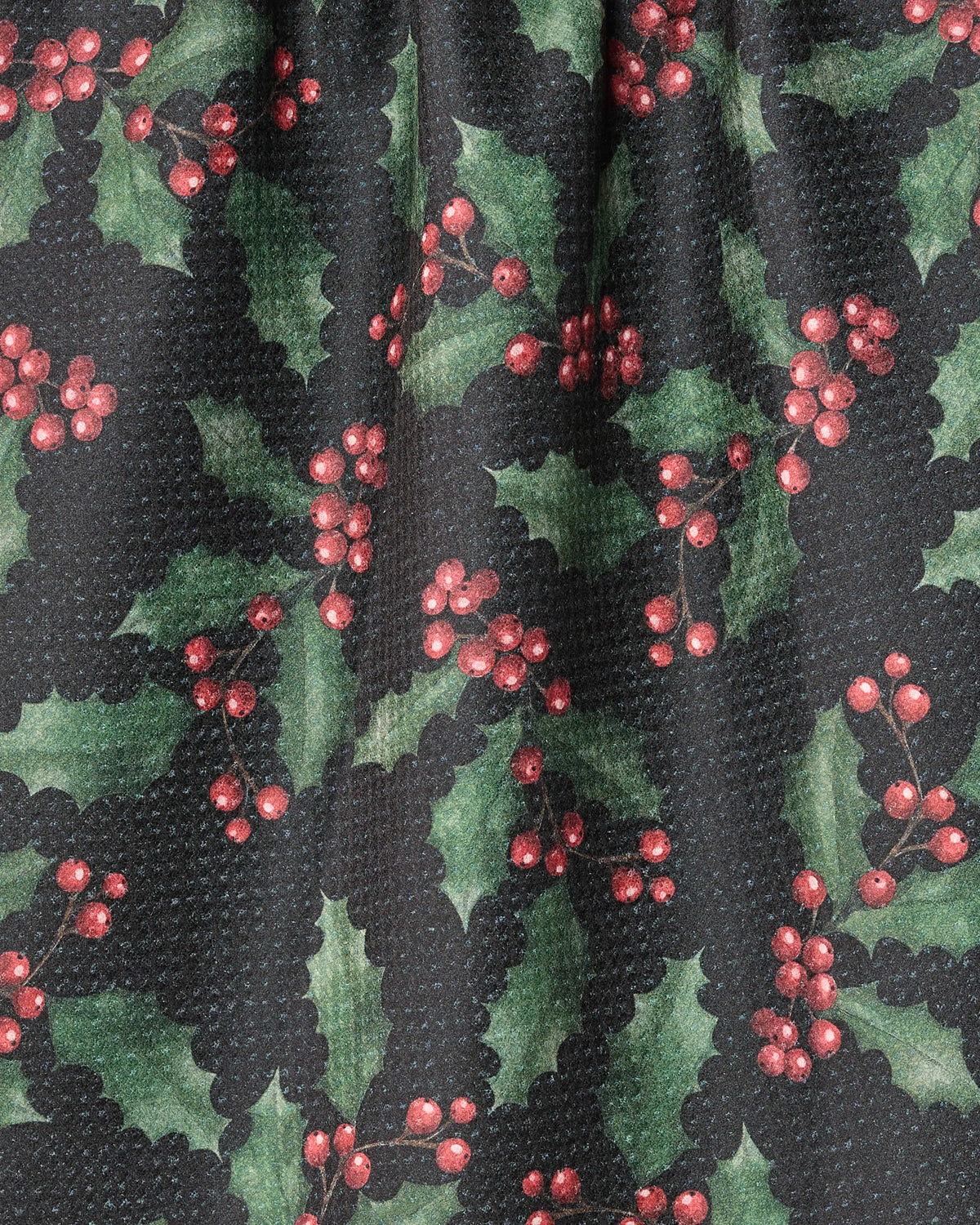 Introducing Holly Night by Geometry: This ultra-absorbent towel features a festive pattern of green holly leaves and clusters of red berries on a textured black background. Crafted from recycled materials, Holly Night combines seasonal charm with eco-friendly practicality—perfect as a holiday kitchen tea towel.