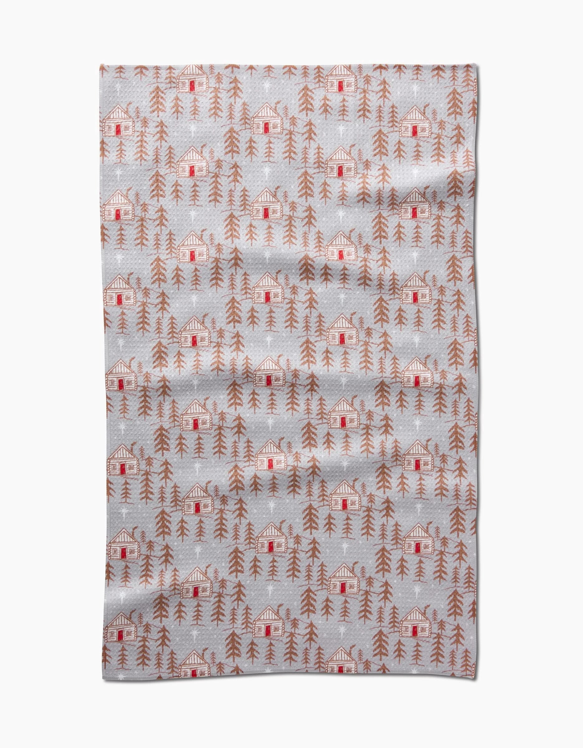 The Homestead blanket by Roxy Marj features red cabins and brown pine trees on a light gray background, creating a cozy, rustic winter vibe. Made from soft, textured recycled materials, it combines comfort with sustainability.