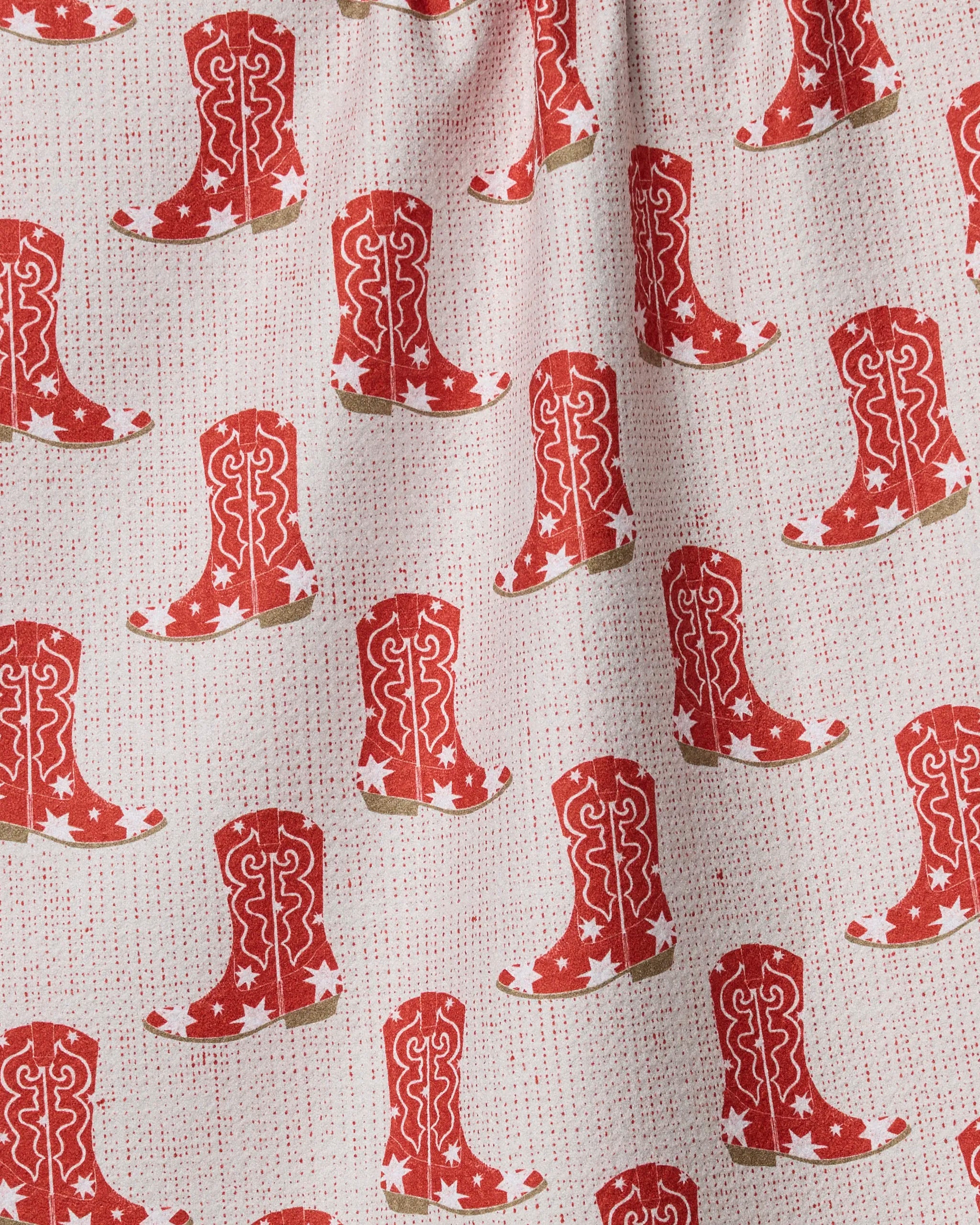 Honky Tonk by Geometry is a textured, slightly gathered fabric ideal for kitchen towels, featuring a repeating pattern of red cowboy boots with white stars and swirls on a light background with small red dots.