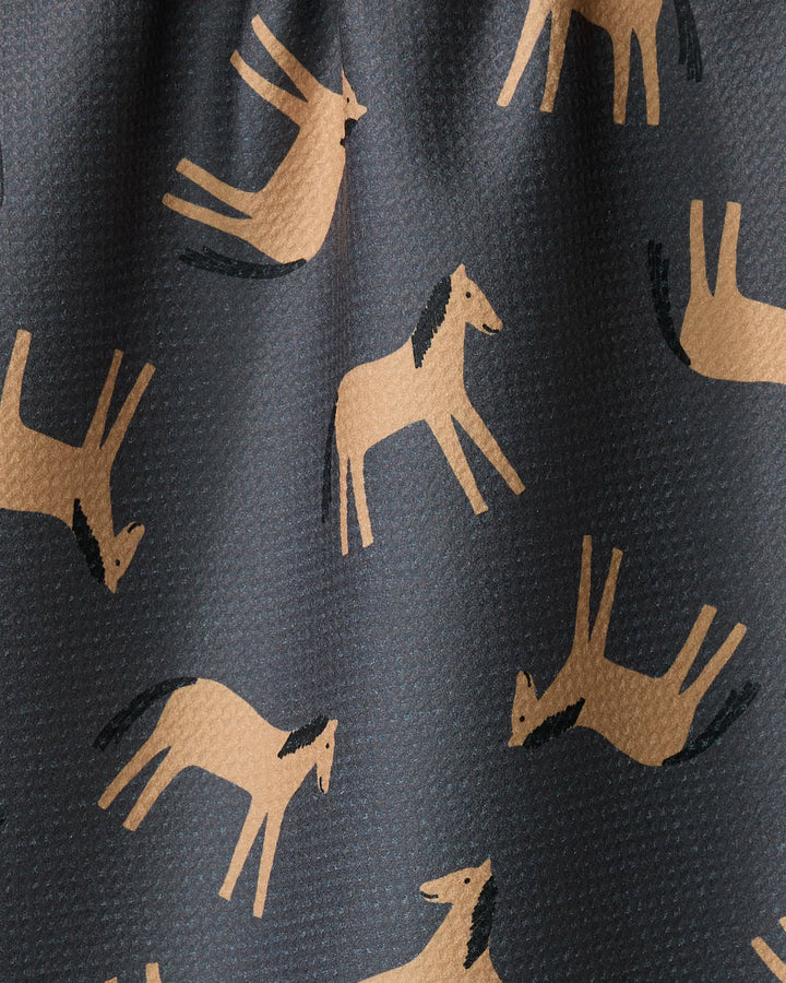 The Coit Creative "Horses" tea towel showcases stylized tan horses in running and jumping poses on a dark background, crafted from recycled materials.