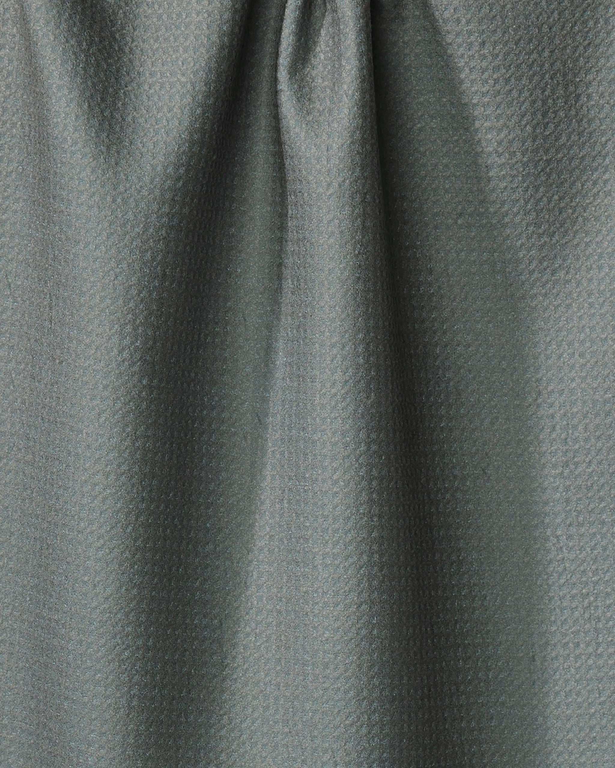 Close-up of Hunter Green fabric by Kailee Wright, featuring a subtle pattern with soft folds and gentle shadows. Crafted from recycled materials, the gray textile showcases delicate highlights and textured detail.