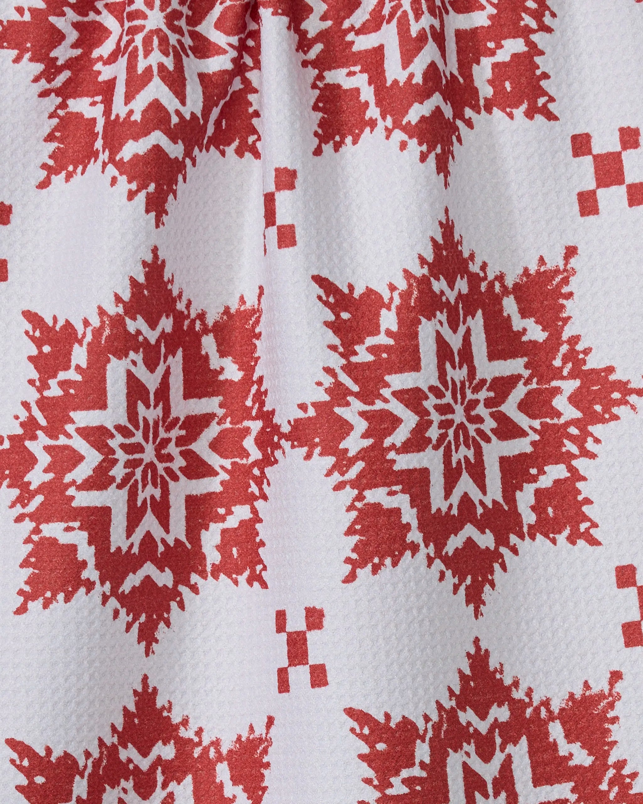 The Geometry Iceflower tea towel features a red and white geometric snowflake pattern on recycled fabric, with bold red shapes, a light background, and a textured, ultra-absorbent surface.