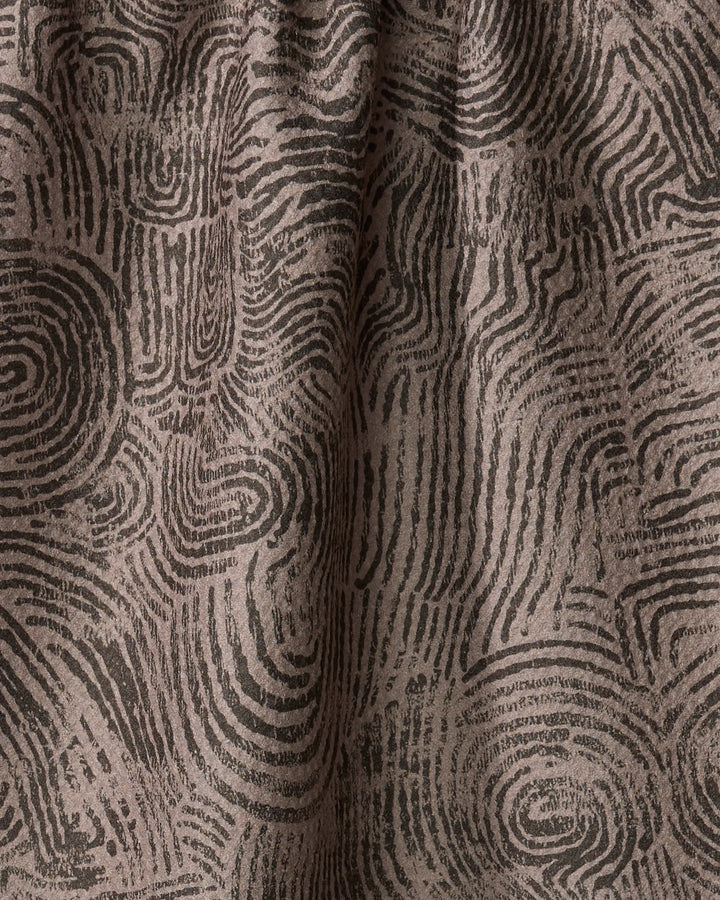 Close-up of Studio Jeannot’s Imprint recycled kitchen towel, featuring a textured pattern of overlapping black fingerprint-like swirls on a brown background with organic curves and subtle folds.