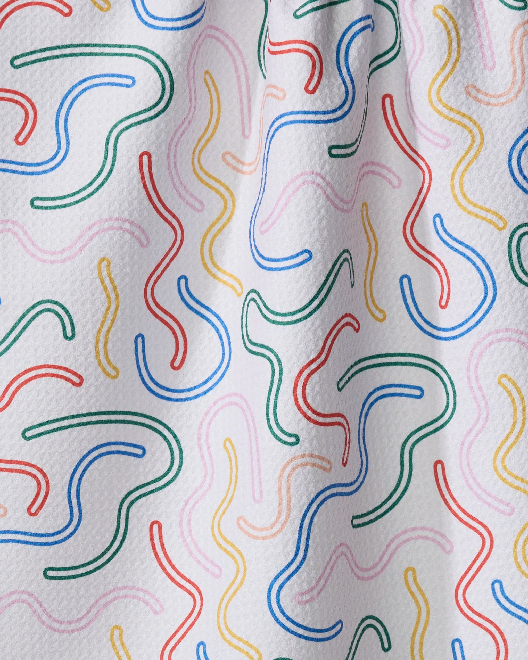 The "In the Moment" tea towel by Happy Hemera features a white textured background with colorful squiggly red, green, yellow, pink, and blue lines in an abstract pattern—an upbeat accent for any kitchen.