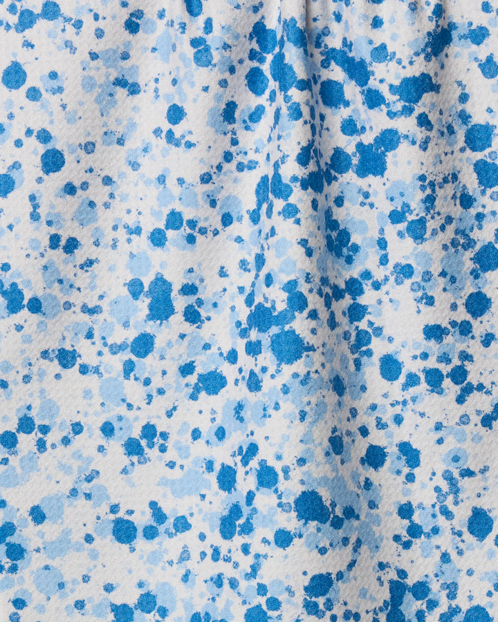 A close-up of Geometry's Indigo Splash fabric, crafted from recycled materials, features a white background with scattered blue splatter patterns in varying shades for an abstract, textured look.