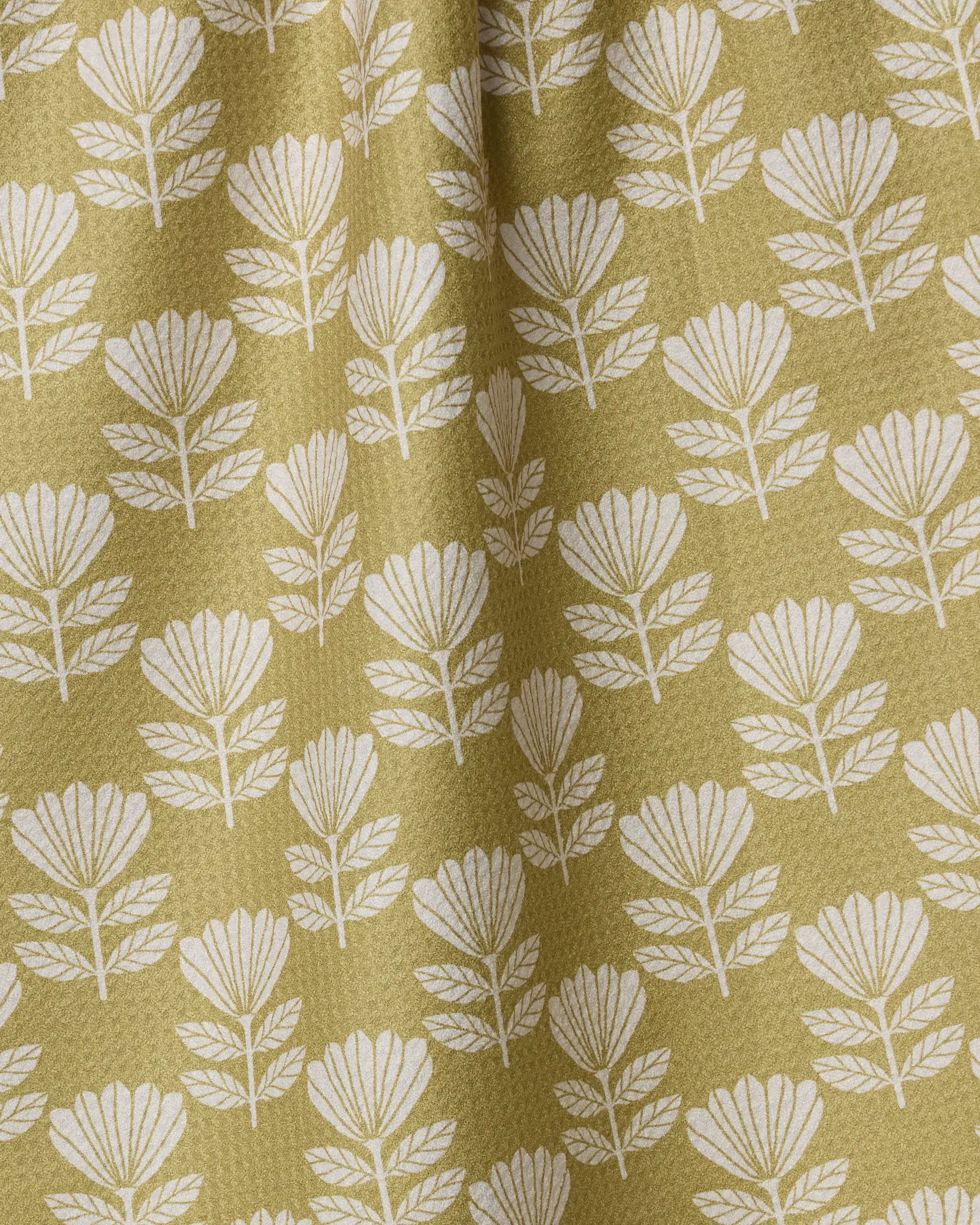 Ingrid by Anna Christian features a white, stylized floral pattern on textured olive-green fabric. This absorbent dish towel's gentle gathers create soft vertical folds and shadows, making it a charming accent for your kitchen.