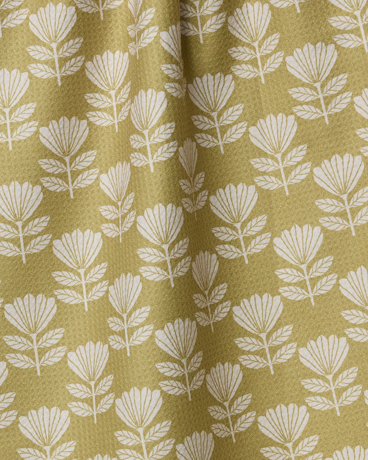 Ingrid by Anna Christian features a white, stylized floral pattern on textured olive-green fabric. This absorbent dish towel's gentle gathers create soft vertical folds and shadows, making it a charming accent for your kitchen.