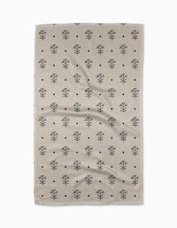 The Inked Bloom tea towel by Cole Strem features a beige, textured design with a repeating black tree-like pattern and small black dots on a white background. Made from recycled materials, it has a naturally wrinkled look.