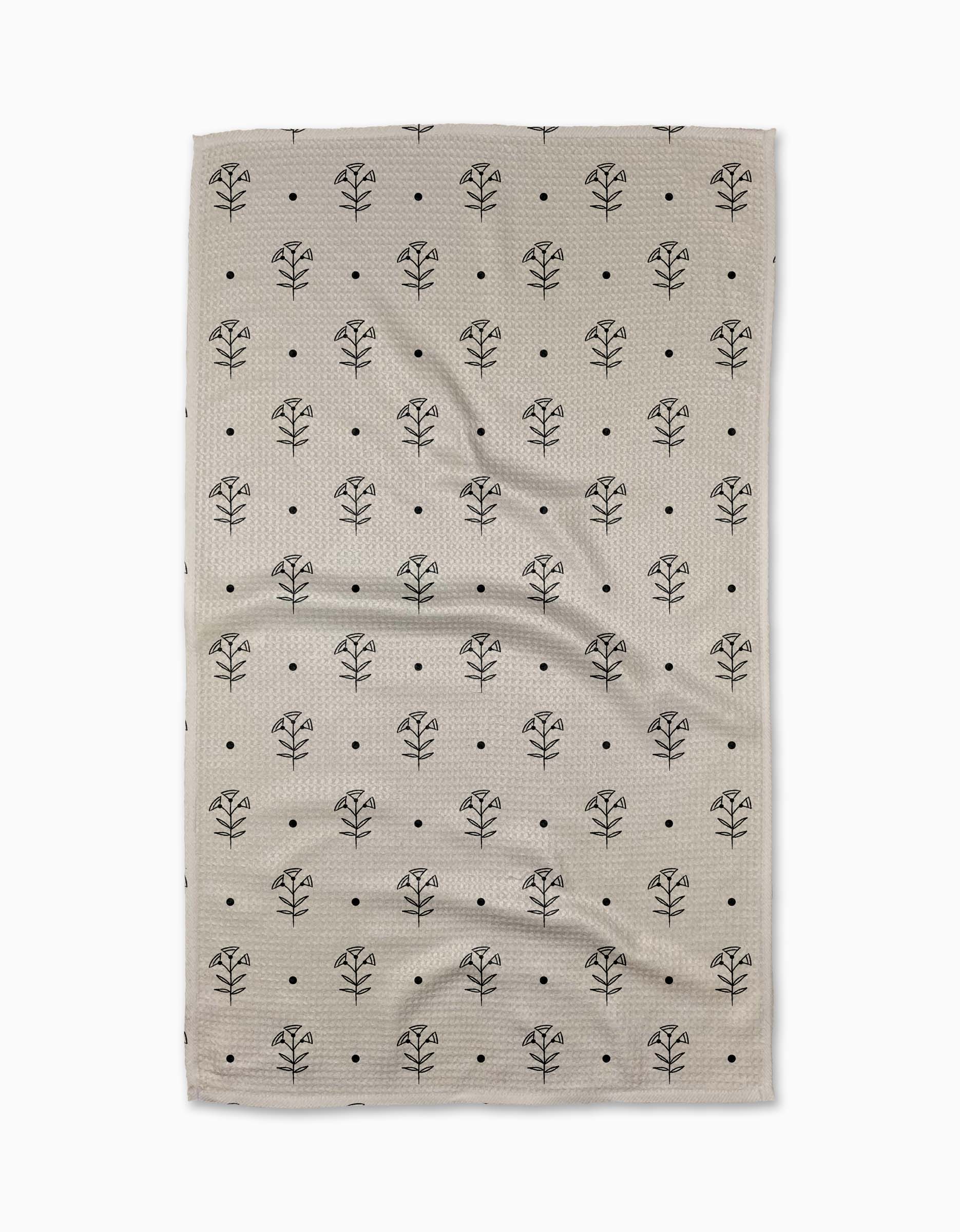 The Inked Bloom tea towel by Cole Strem features a beige, textured design with a repeating black tree-like pattern and small black dots on a white background. Made from recycled materials, it has a naturally wrinkled look.