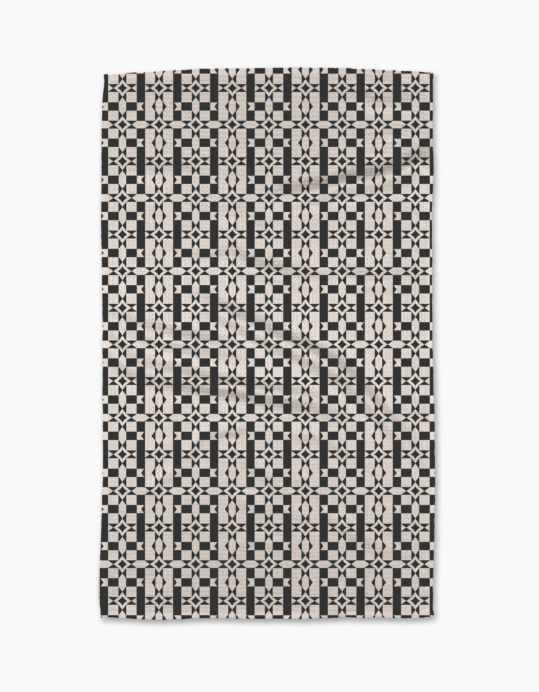 The Intermission Tea Towel by Geometry is made from Geoweave™ fabric and features a black and cream geometric pattern of repeating squares, diamonds, and stars forming an intricate, symmetrical tiled design.