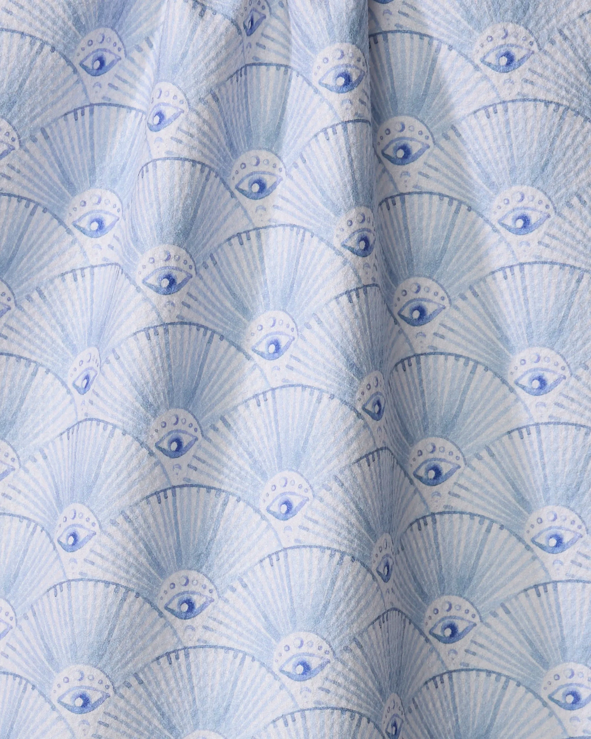 Add charm to your kitchen with Maayan Alper-Swan’s “Into The Mystic” kitchen towel, showcasing blue eyes, crescent moons, and fan shapes in soft blue and white tones.