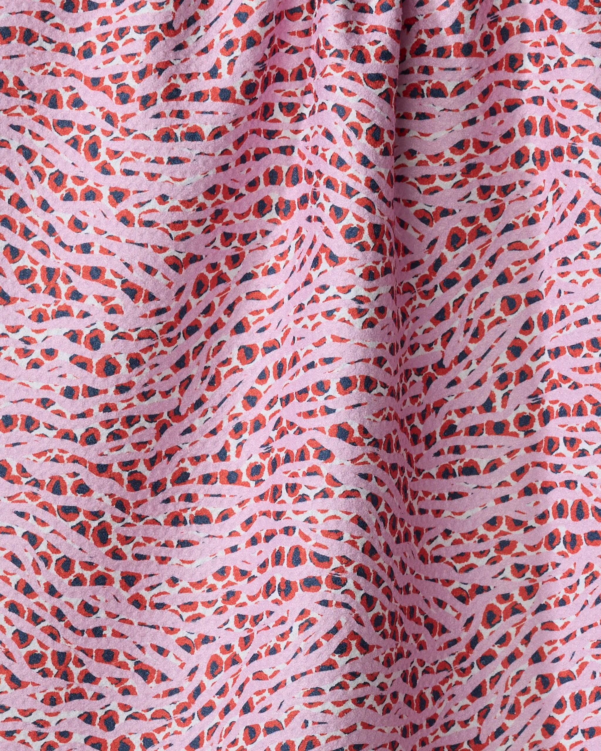 Close-up of Happy Hemera's "Into the Wild" kitchen towel, crafted from recycled materials and featuring a wavy, abstract pattern in pink, red, and black with soft texture and irregular shapes.