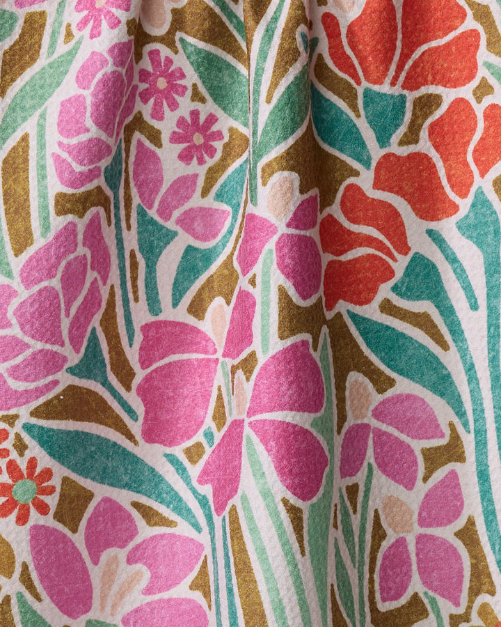 A close-up of the Janae kitchen towel by Amy MacCready, showcasing a textured, recycled fabric with a gathered floral print—pink, red, and orange flowers with green leaves and olive accents on white.