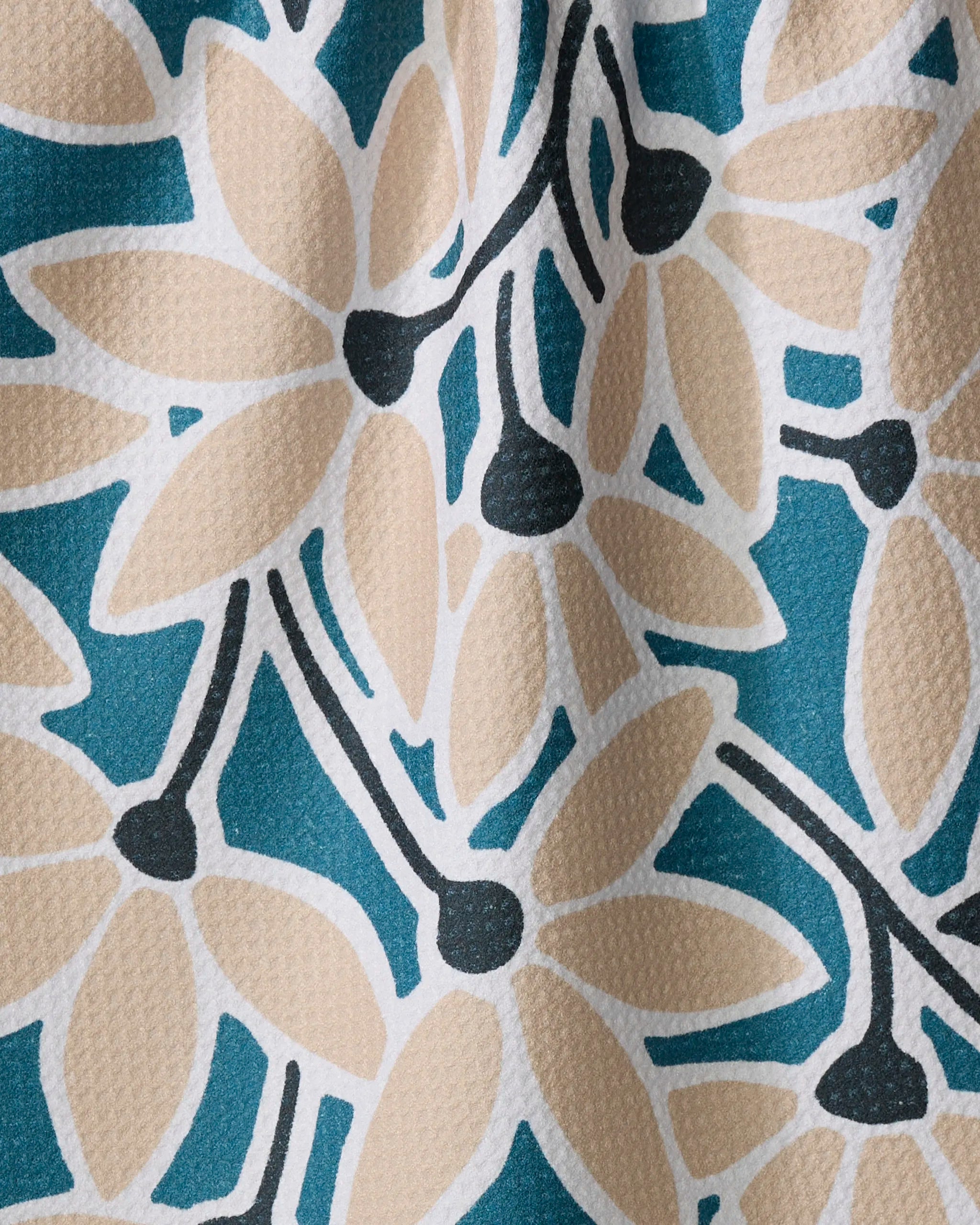 Close-up of the Janine dish towel by Amy MacCready, featuring a textured, absorbent surface with bold beige-petaled flowers, black centers and stems, and white outlines on a teal background.