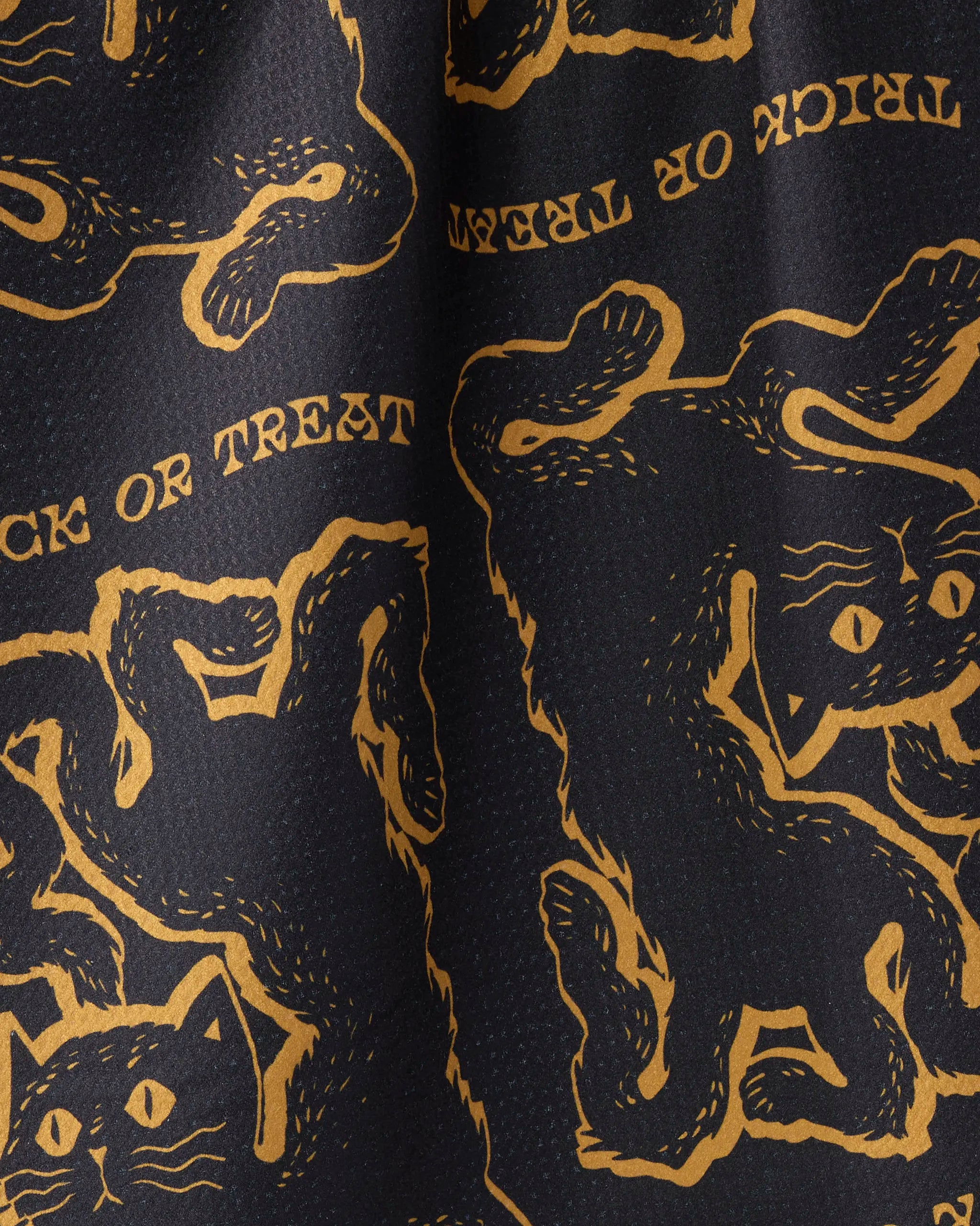 Close-up of Geometry's Jinx tea towel, ultra-absorbent and featuring playful orange-black cats and "TRICK OR TREAT" text on a black background.
