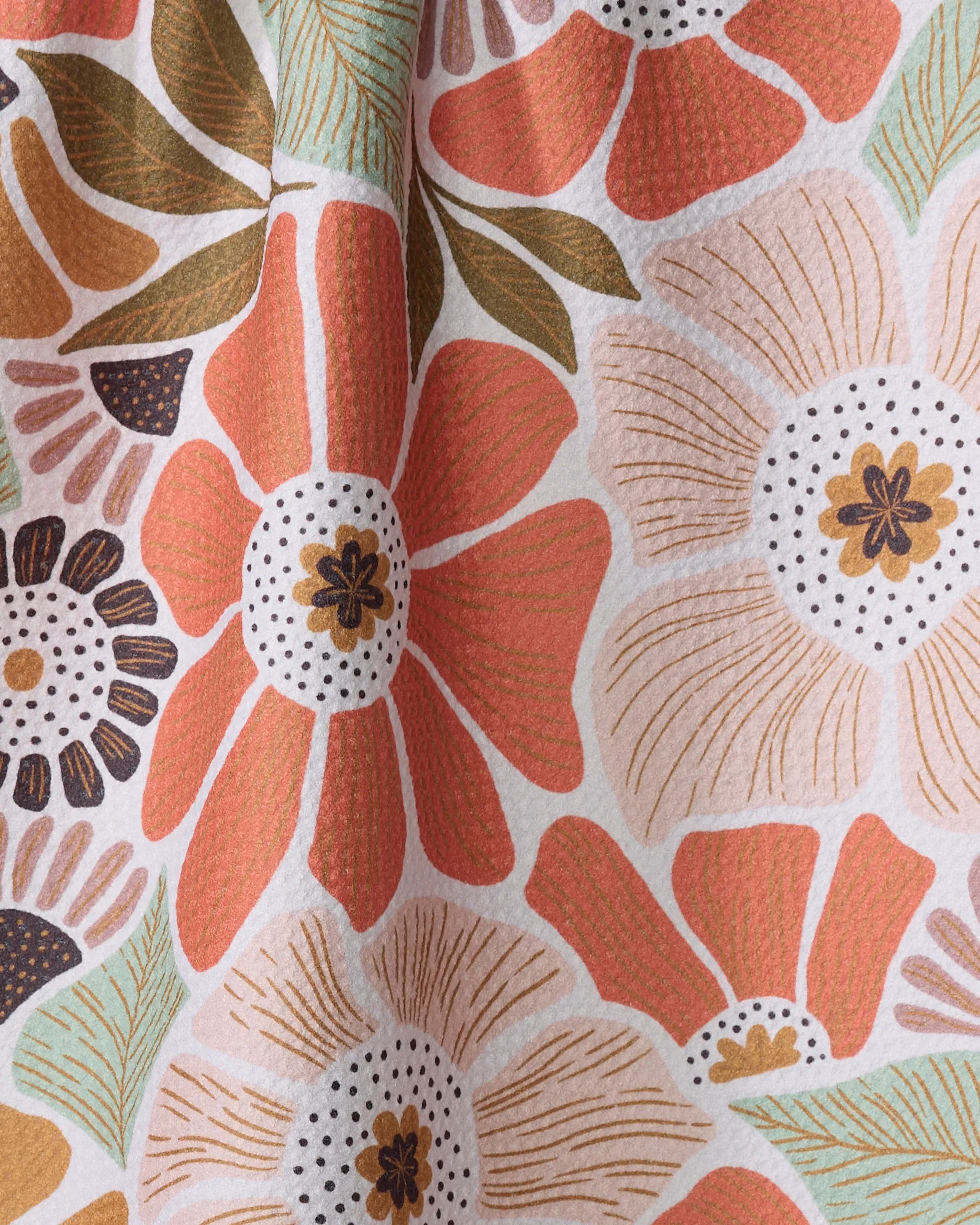 A close-up of the Jorah tea towel by Amy MacCready, featuring recycled materials and a vibrant floral pattern with large orange, peach, and cream flowers, green leaves, and black accents on a white background.
