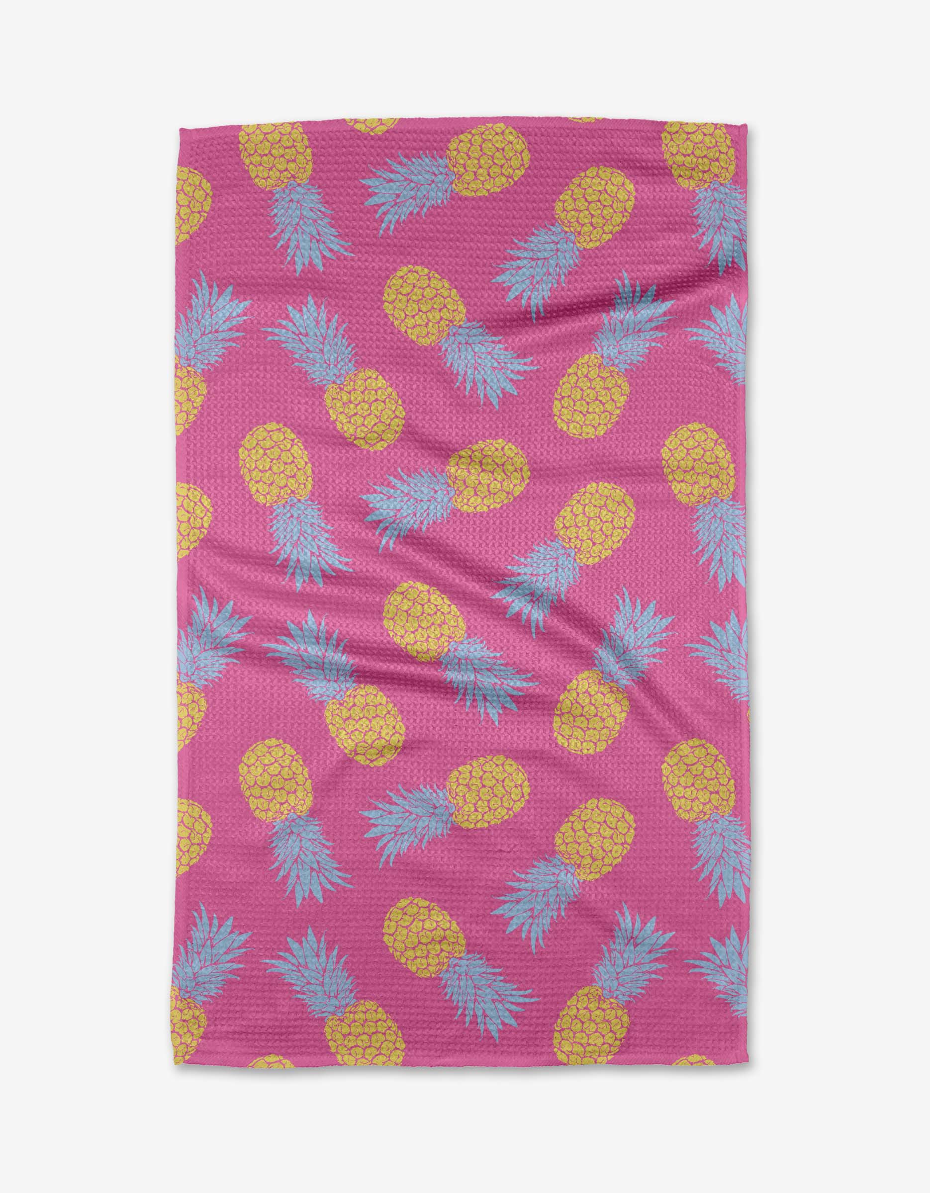 The Juicy Pineapples towel by Ashley Celena features a pink backdrop with yellow pineapples and blue-green leaves, made from ultra-absorbent Geoweave fabric for superior drying.