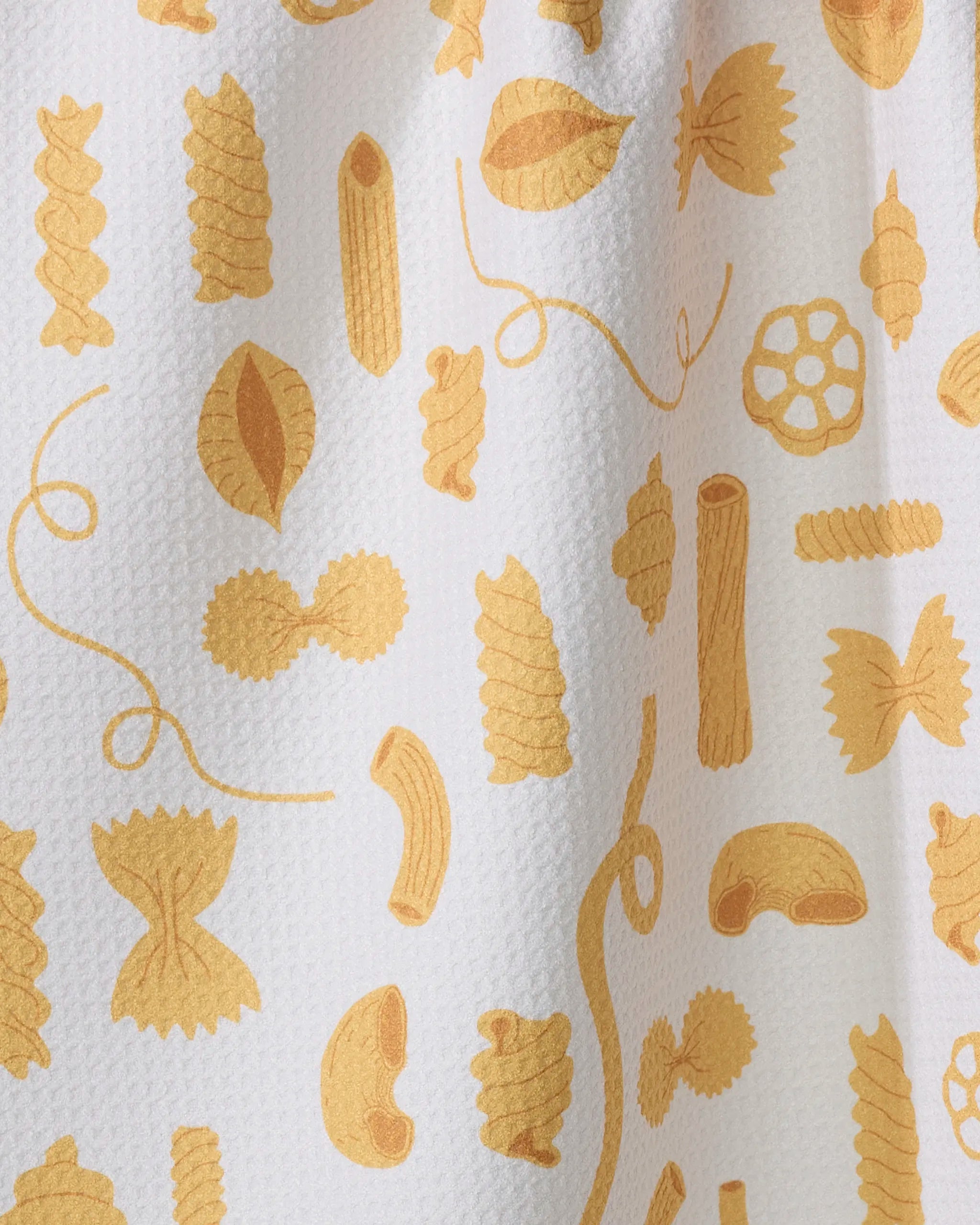 The Vaishali Design Studio 'Just Add Sauce' tea towel features playful yellow penne, fusilli, farfalle, rotini, and spaghetti shapes scattered on white textured fabric. This ultra-absorbent towel adds fun to your kitchen.