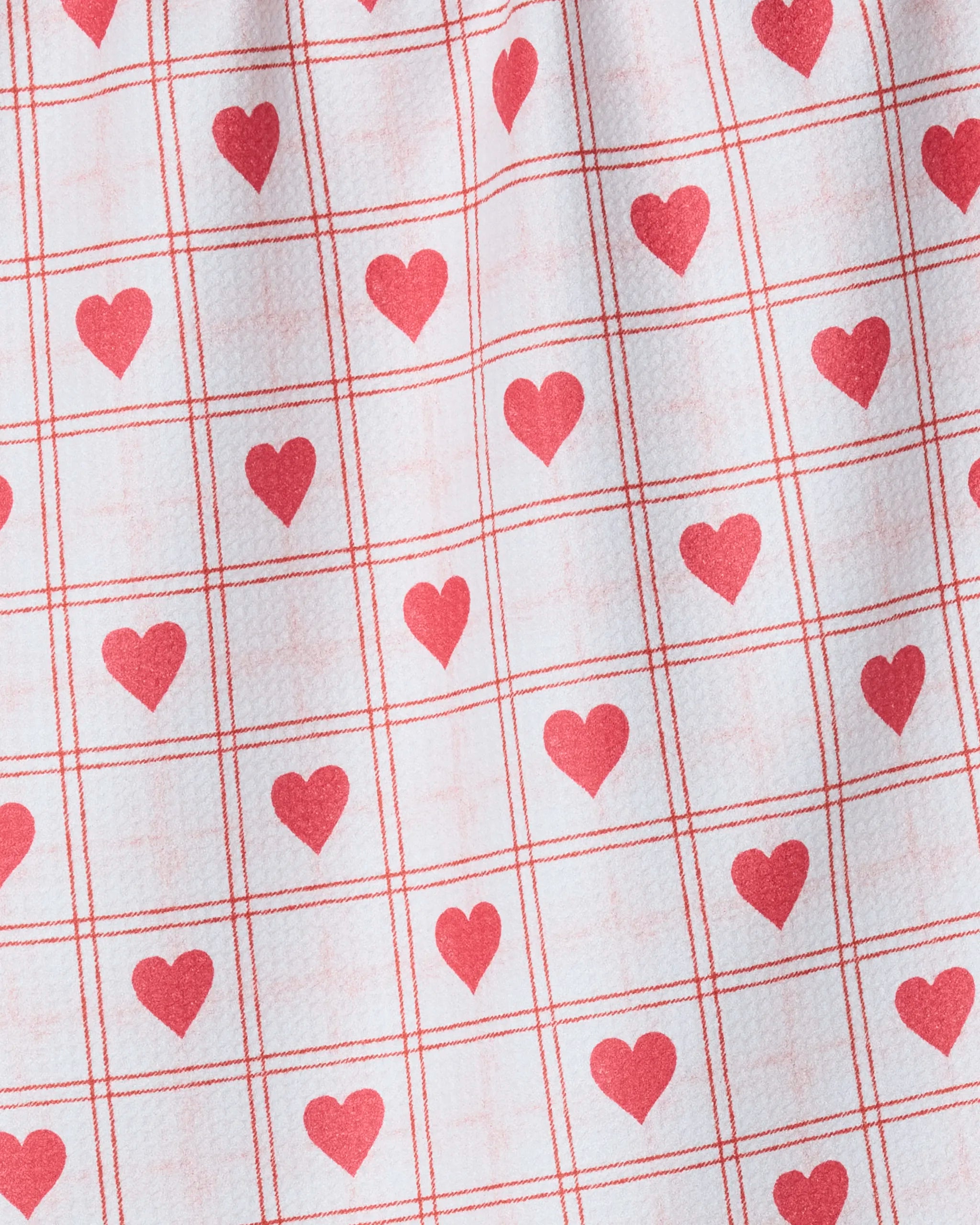 The Kind Spirit tea towel by Geometry features a white base with a red grid and heart pattern, adding warmth and style to your kitchen. Made from recycled materials, it's an eco-friendly choice for any home.