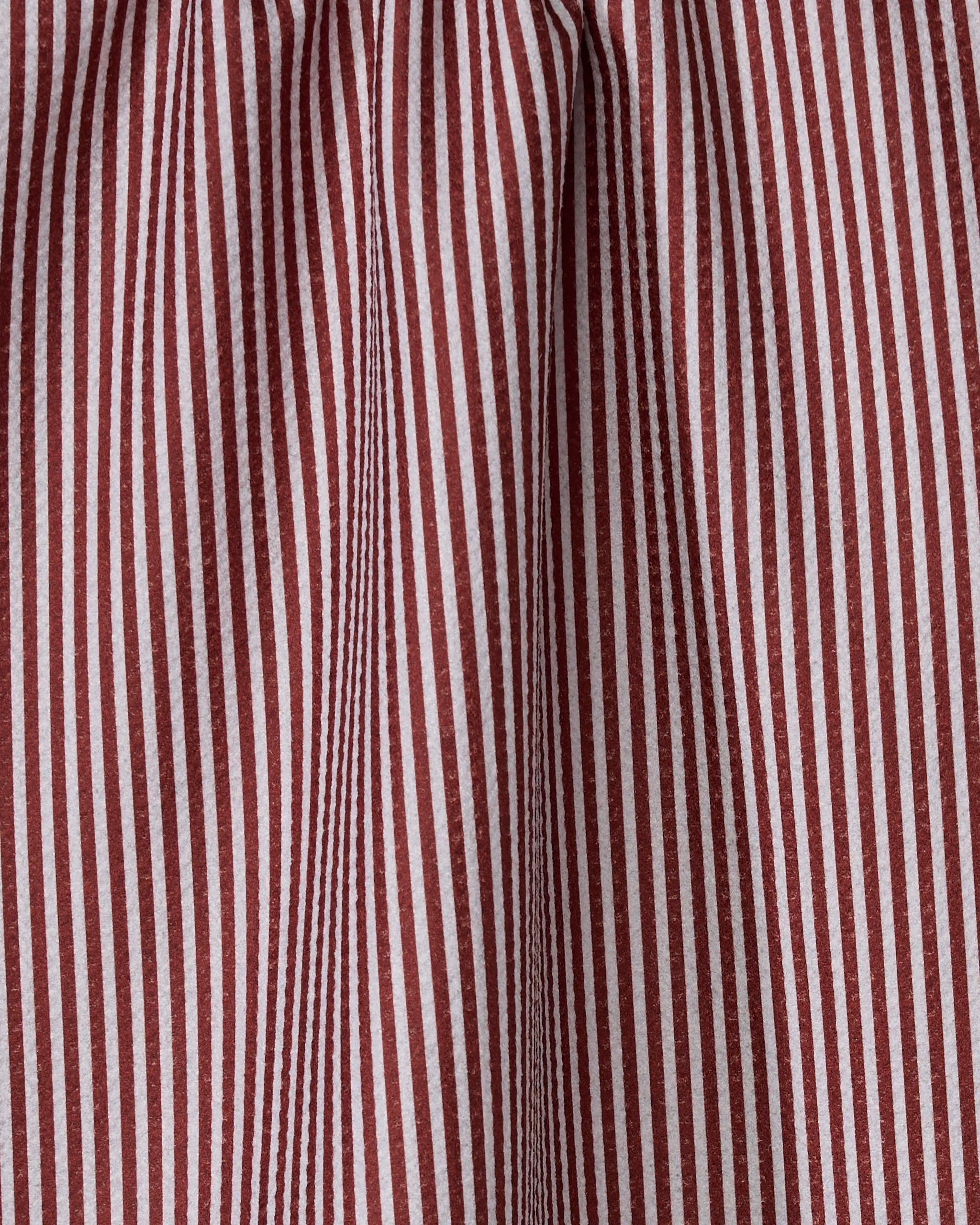 Close-up of Geometry's Kringle towel, featuring vertical red and white stripes. The quick-drying material is slightly gathered, creating folds that alter the stripe direction.