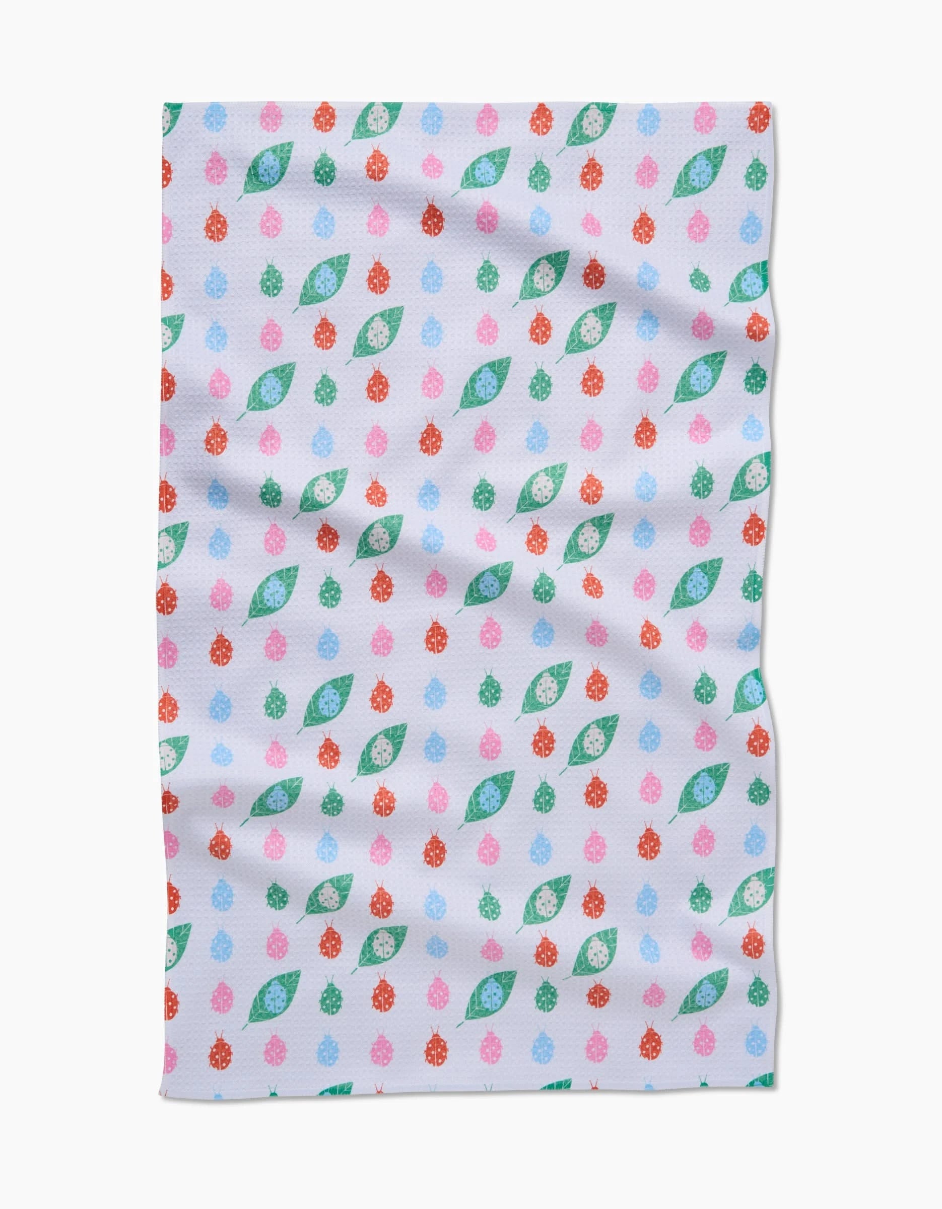 The Ladybug Leaf tea towel by Elisabeth Wing features a repeating pattern of red, pink, and blue ladybugs with green leaves on white, all crafted from recycled materials for a sustainable touch.