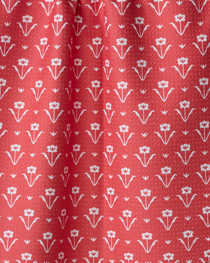 Close-up of the Ladylake - Red tea towel by The Buy Guide. Ultra-absorbent red fabric features a white floral pattern, with gentle folds and soft shadows near the gathered top.