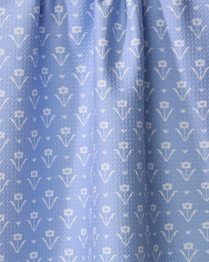 The Buy Guide’s Ladylike - French Blue towel features a light blue color with a repeating white floral pattern and stylized flowers and leaves. The fabric is slightly gathered or pleated at the top for added texture.