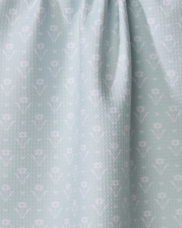 The Buy Guide's Ladylike - Mint is an absorbent light blue dish towel with a subtle textured pattern and small white floral motifs. The fabric gathers at the top, forming gentle folds and soft shadows.
