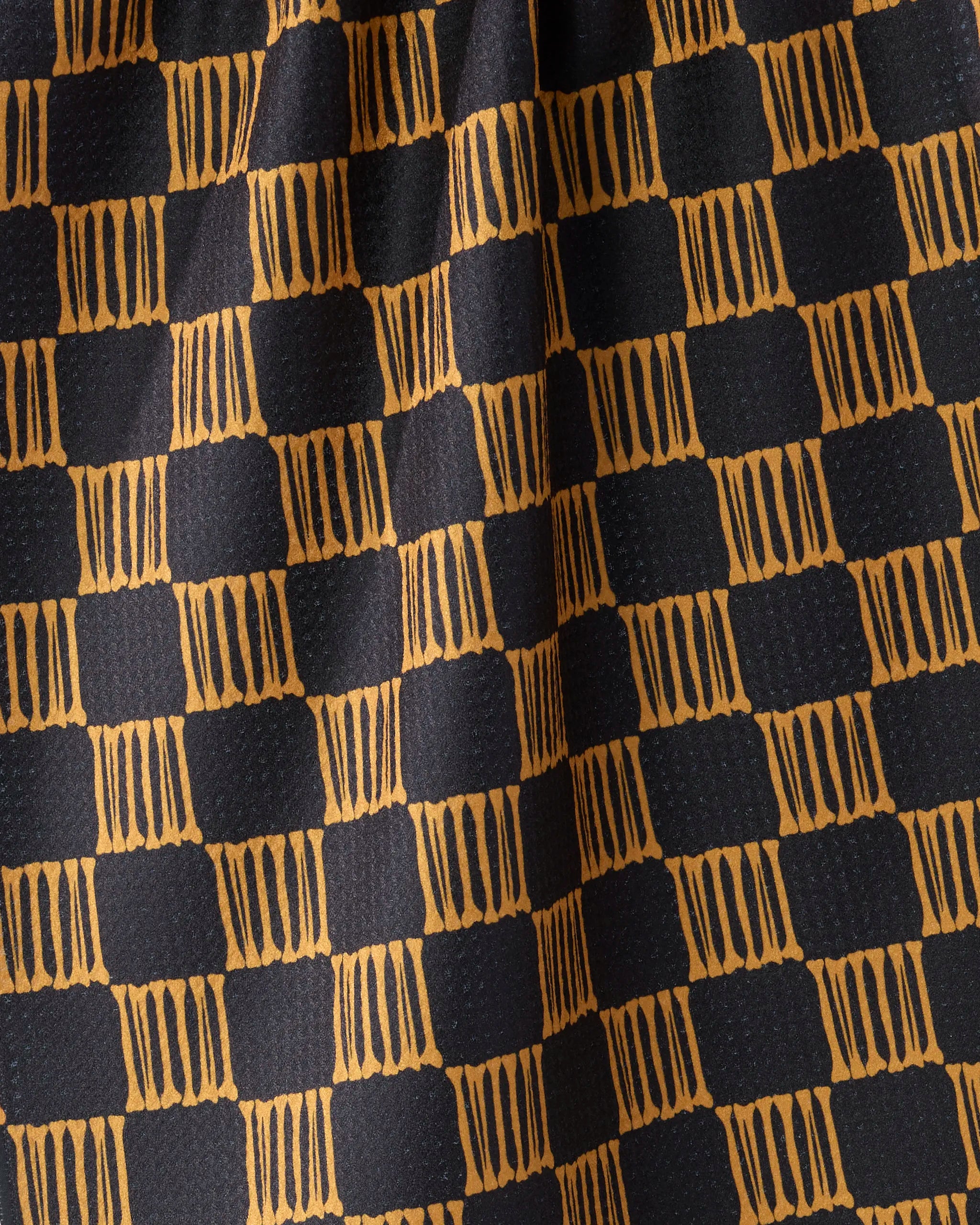 A close-up of Geometry’s Lantern Grid kitchen towel, featuring a checkered pattern with alternating black and yellow-orange squares accented by vertical lines for a textured, geometric look. Made from recycled materials for eco-friendliness.