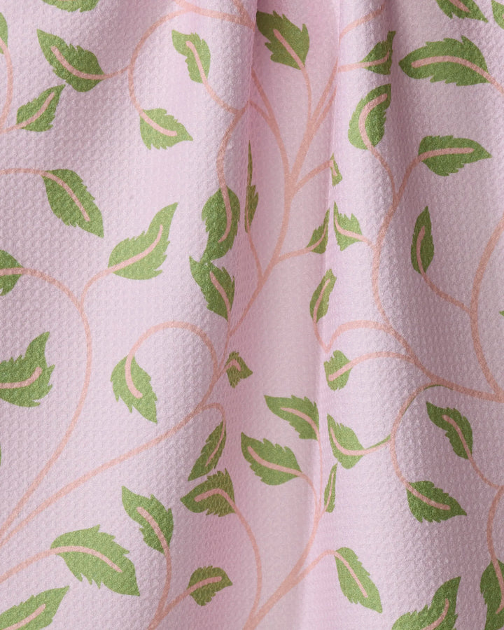 Close-up of the Leafy Maze tea towel by Jasmine Blooms Designs, featuring a textured pink surface with green leafy and subtle beige vine patterns, crafted from recycled materials for a soft, decorative touch.
