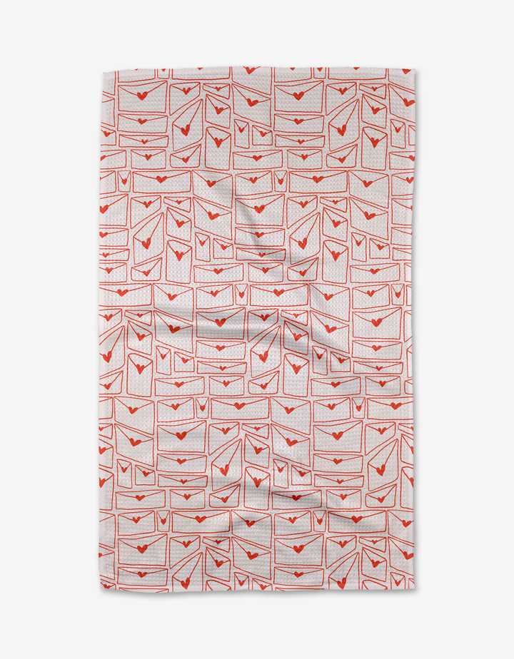 The Kayla Ann Letters of Love dish towel is white and features a grid of red-outlined envelopes, each sealed with a small red heart.