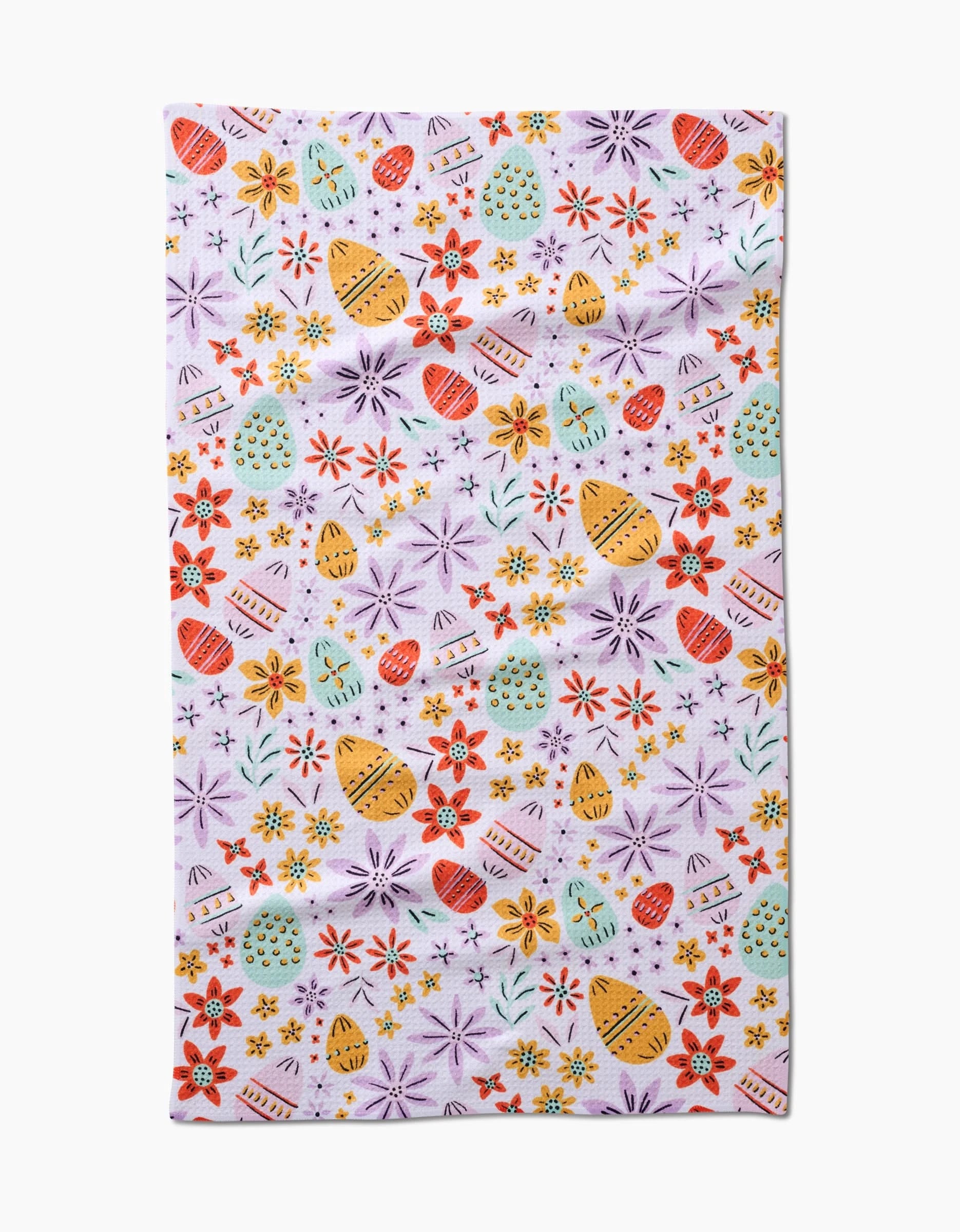 The Lilith tea towel by Amy MacCready showcases a vibrant pattern of decorated Easter eggs and flowers in red, yellow, orange, and purple on white. Made from quick-drying recycled materials for eco-friendly use.