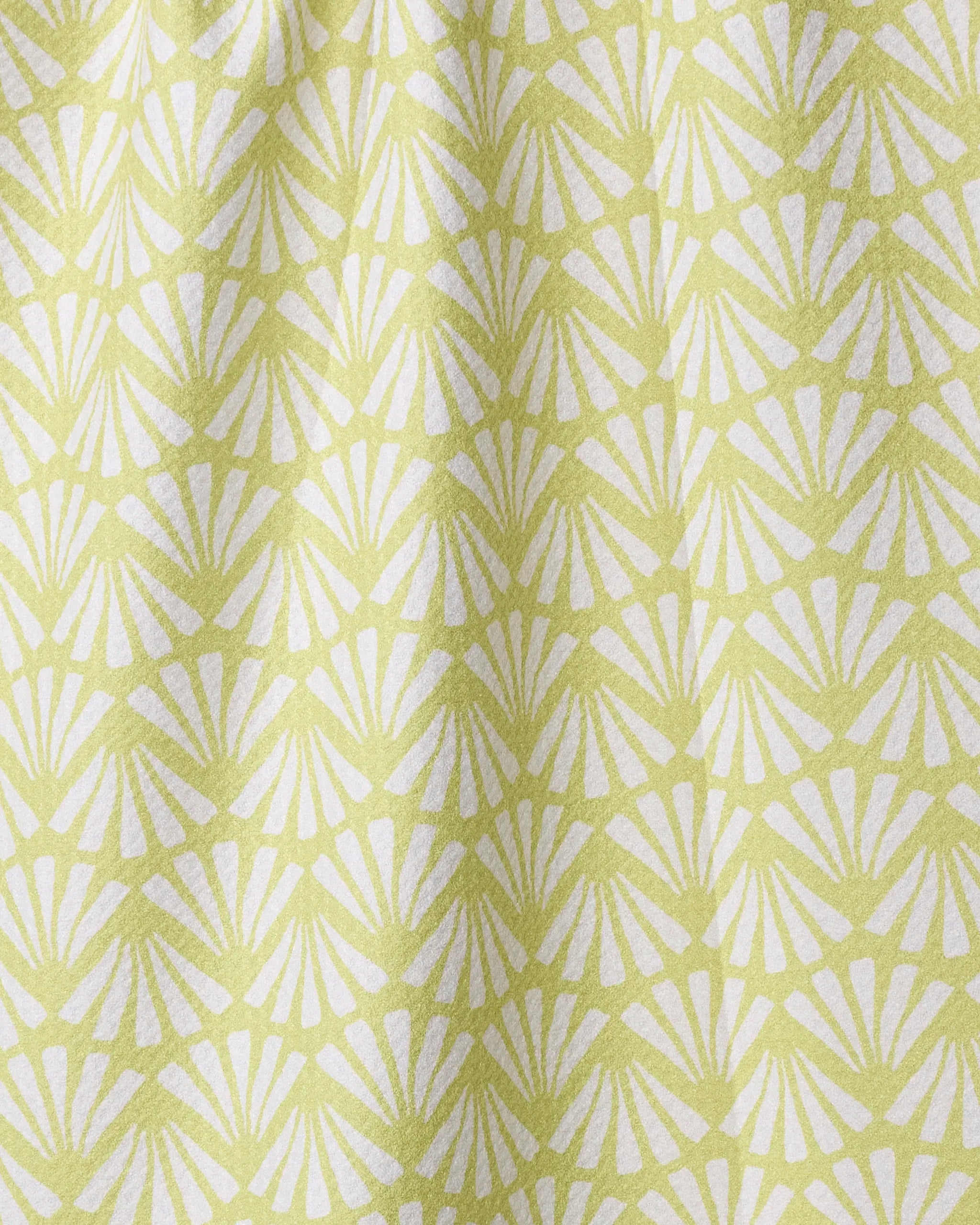 The Lime Blossom kitchen towel by Geometry features a repeating white fan or shell pattern on light green, creating a geometric and textured look. Made from recycled materials, the soft fabric drapes gently.