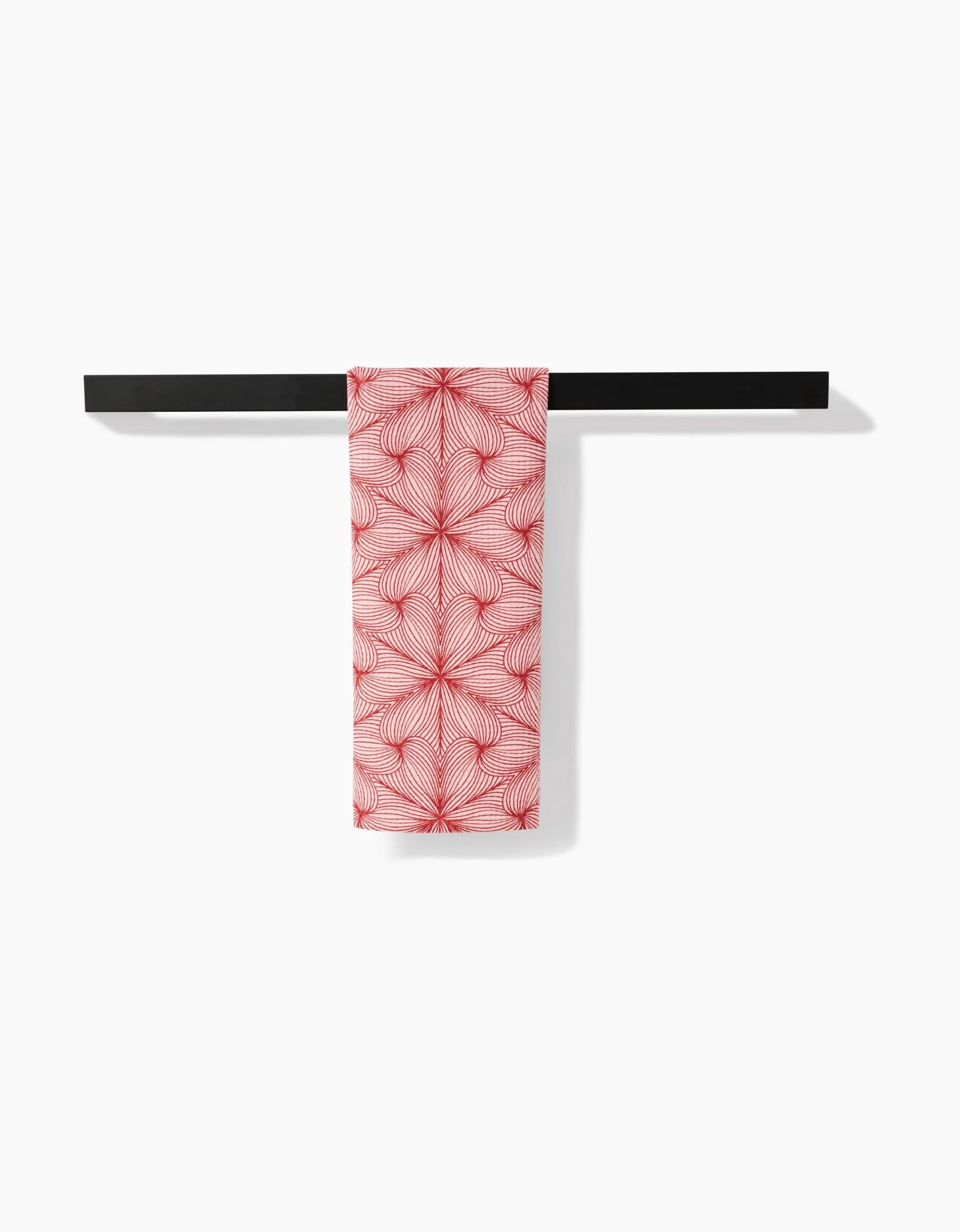 The Marta Harvey Lined recycled kitchen towel with a geometric red and white design is neatly draped over a black towel bar against a plain white background.